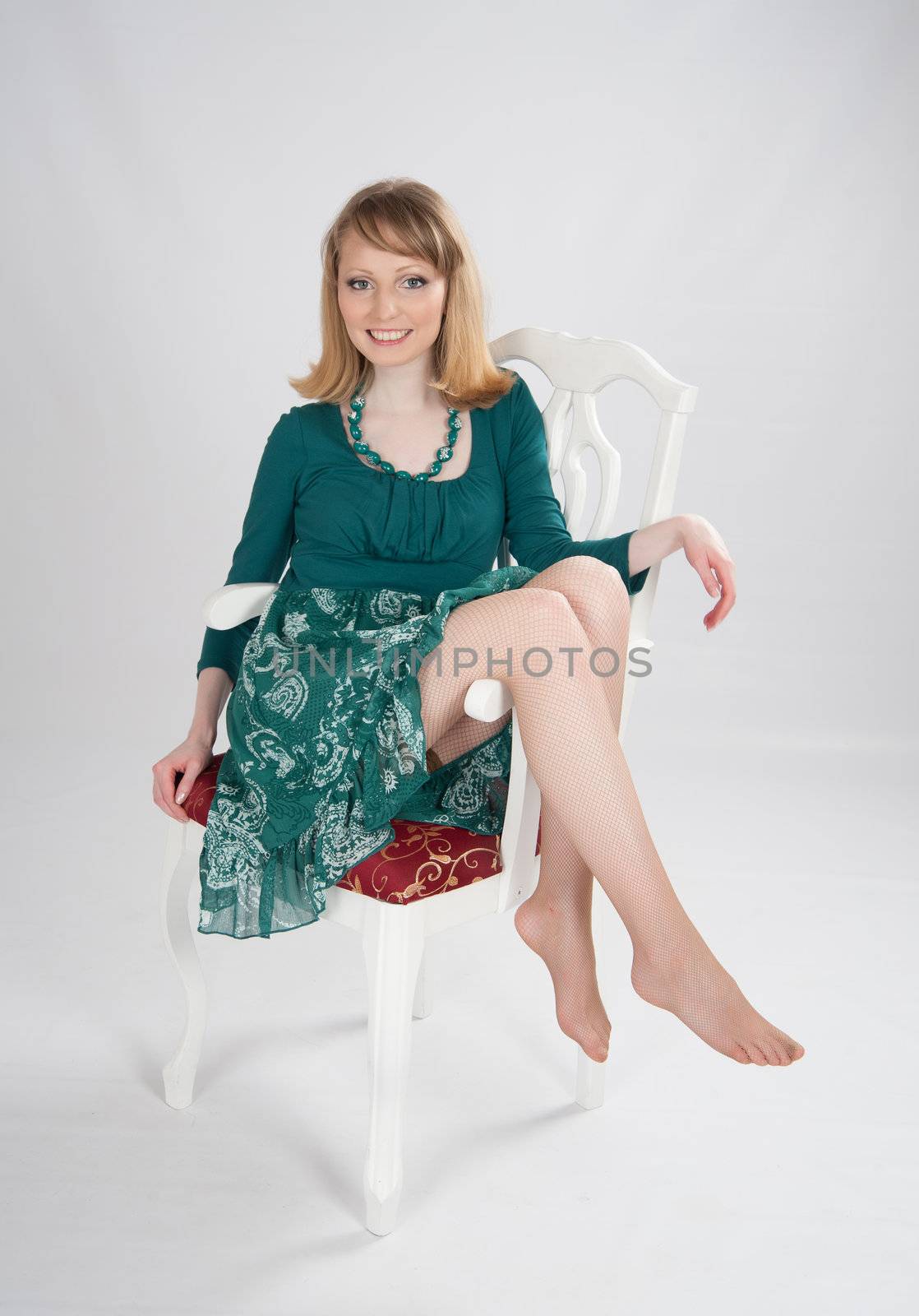 beautiful woman in a green dress sitting on a chair