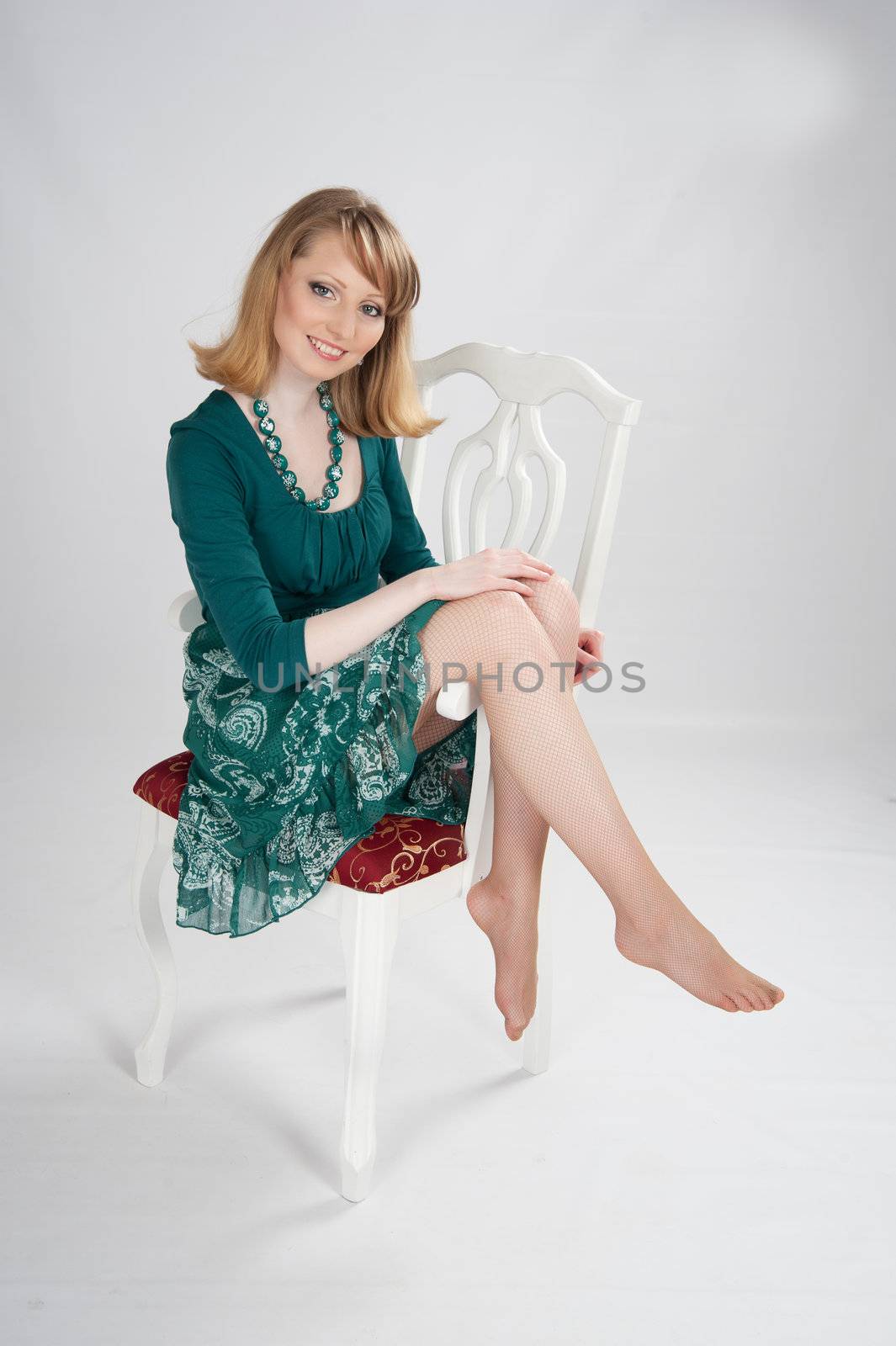 beautiful woman in a green dress sitting on a chair