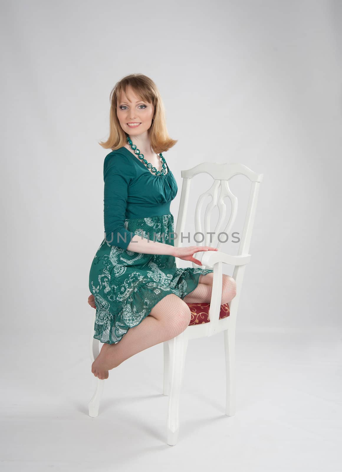 beautiful woman in a green dress sitting on a chair