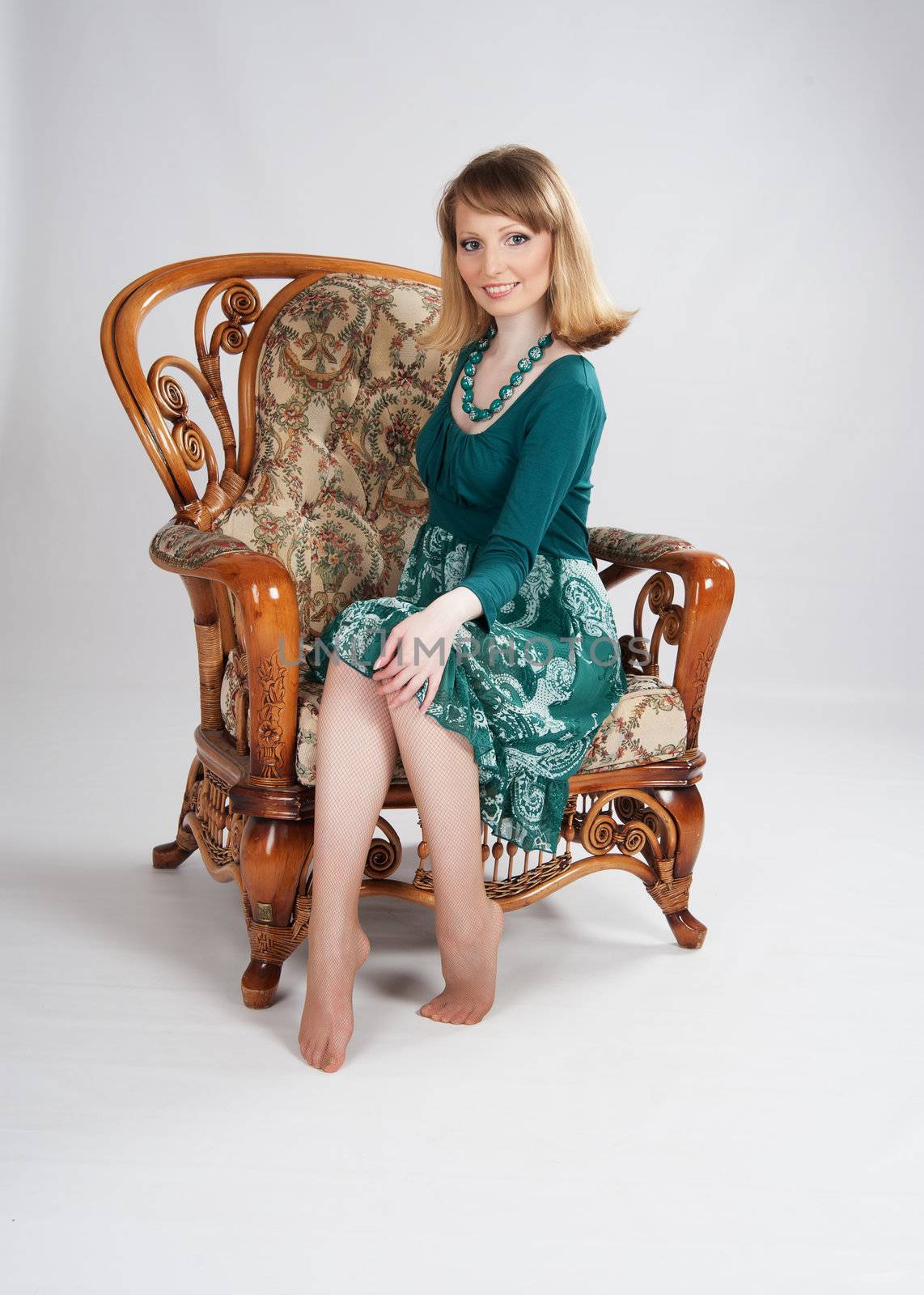 beautiful woman in a green dress sitting on a chair