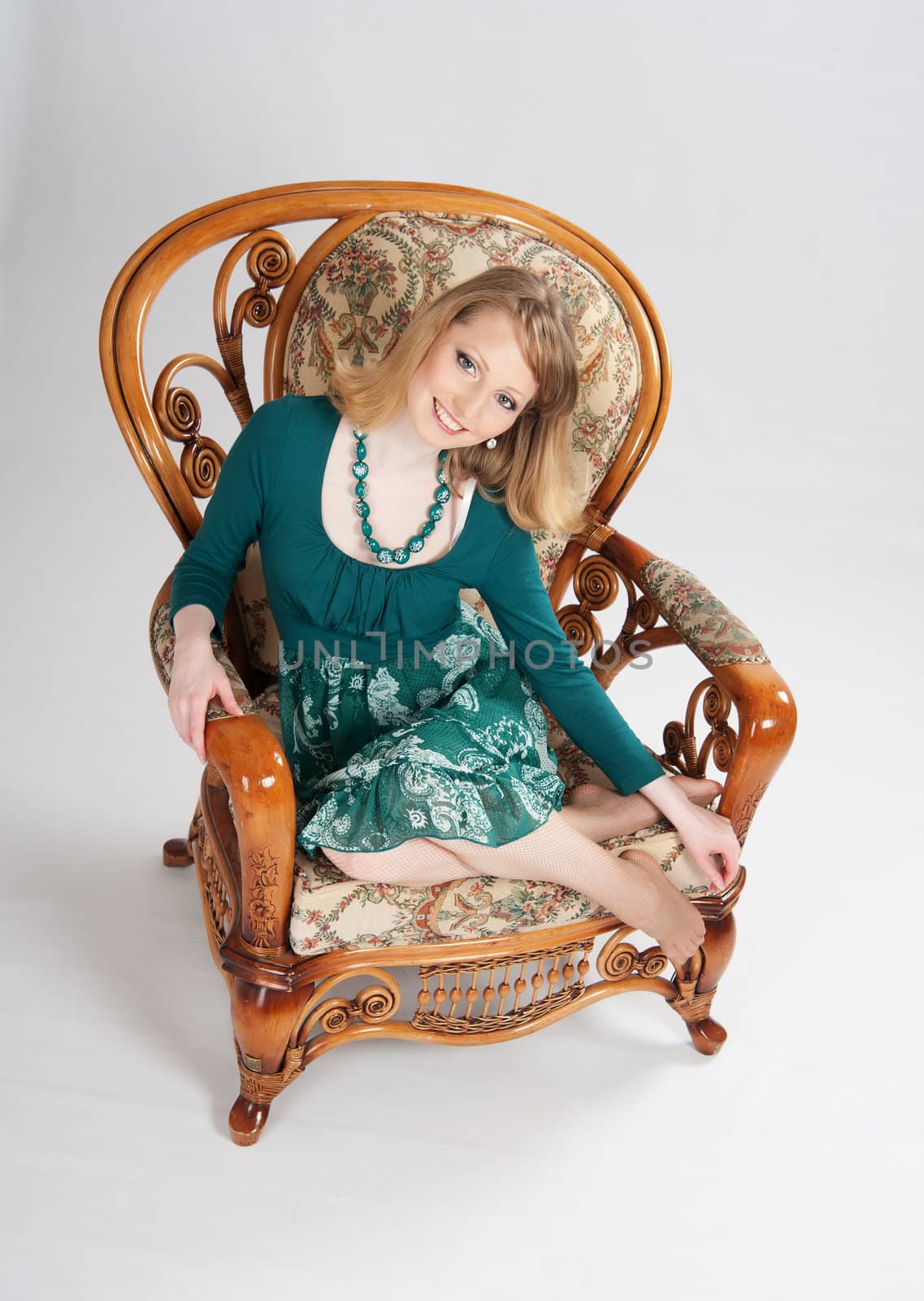 beautiful woman in a green dress sitting on a chair