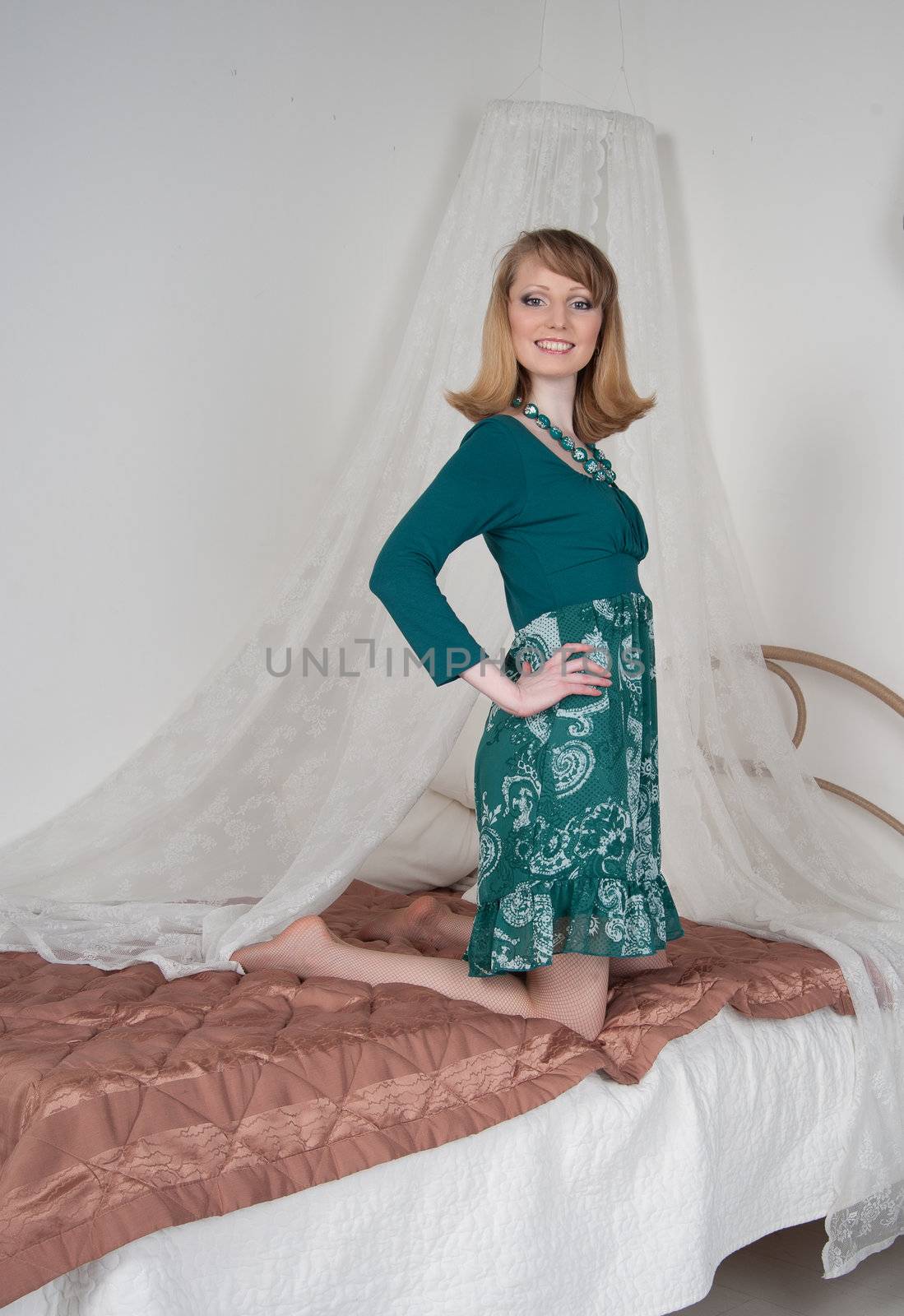 Sexy woman in green dress on the bed