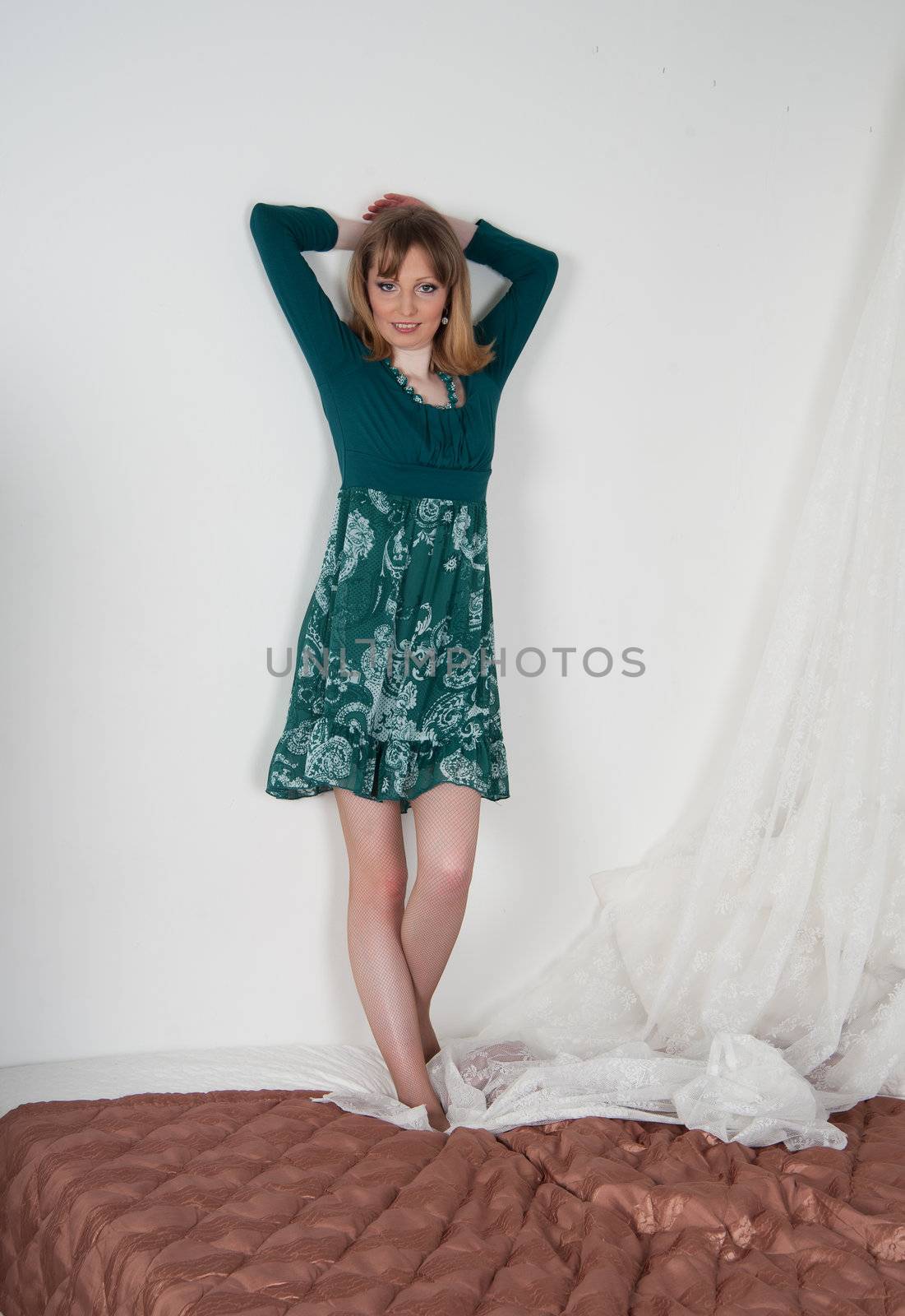 Sexy woman in green dress on the bed