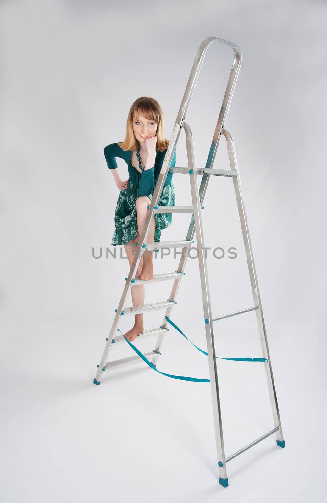 beautiful woman in a green dress standing on a stepladder