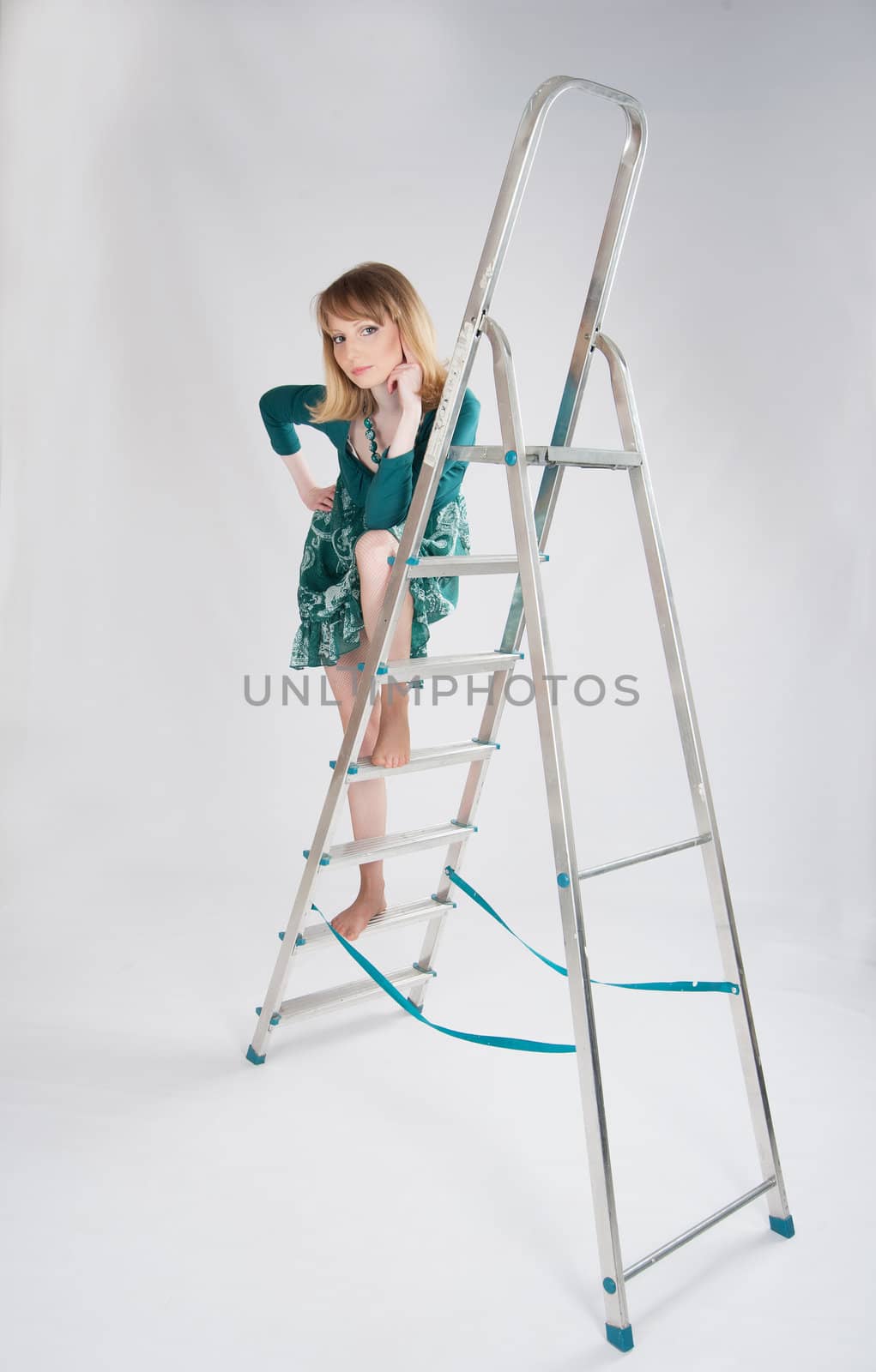 beautiful woman in a green dress standing on a stepladder