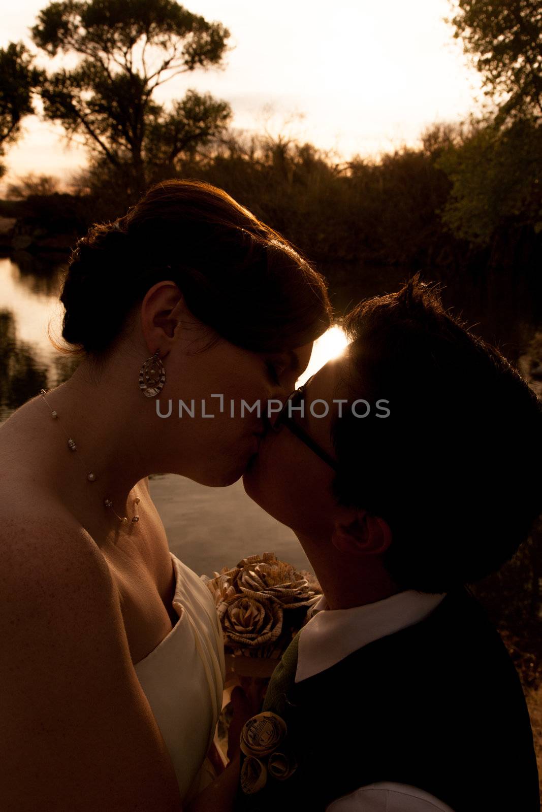 Romantic lesbian couple kissing near sunset outdoors