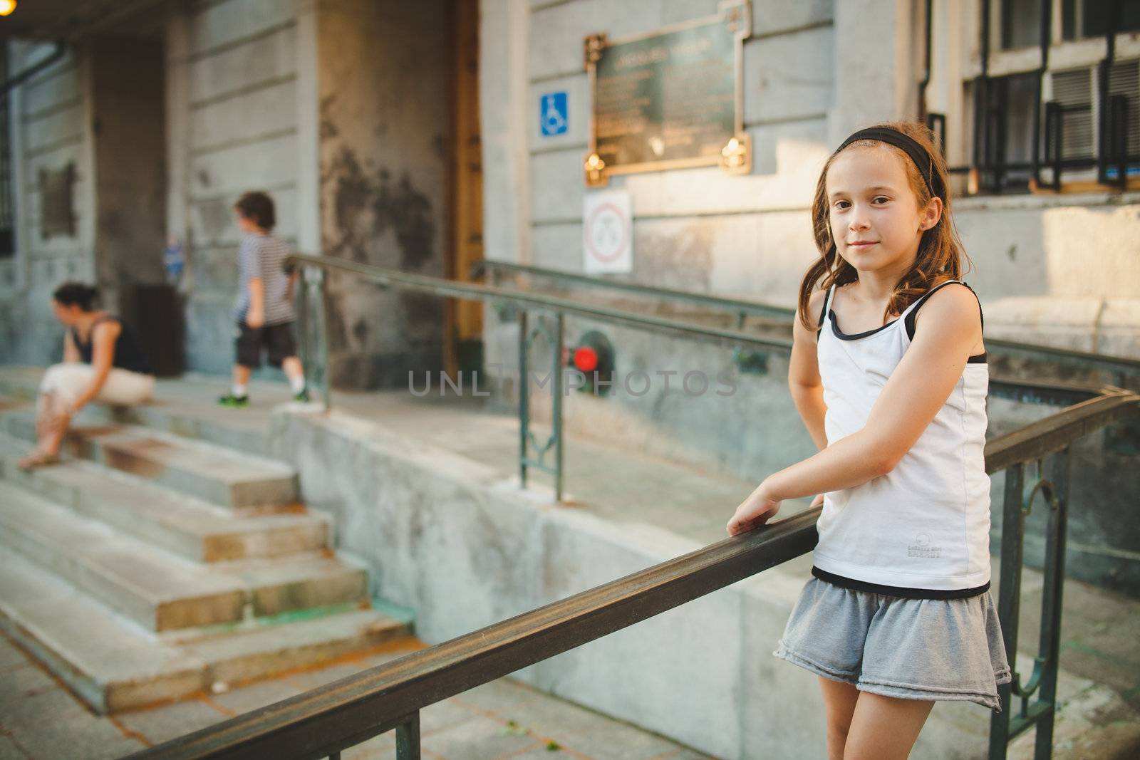 Girl standing outside while her brother is running around