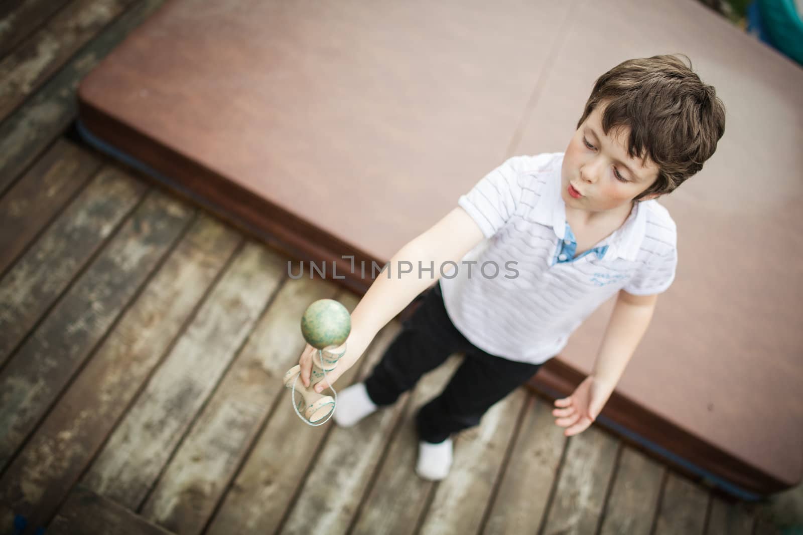 Boy playing cup and ball by Talanis