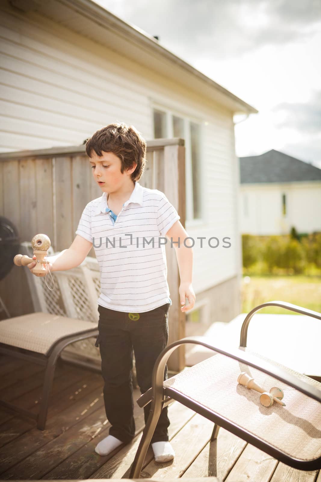 Boy playing cup and ball outside on a patio