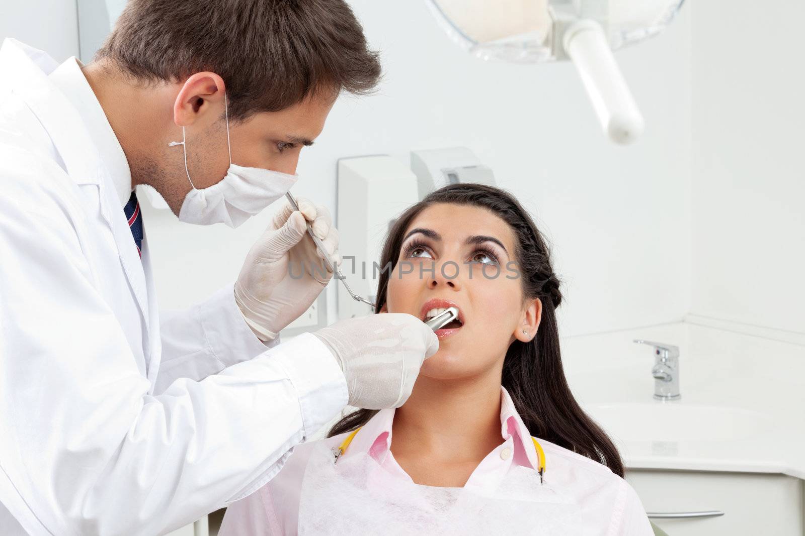 Young male dentist examining patient's mouth in clinic