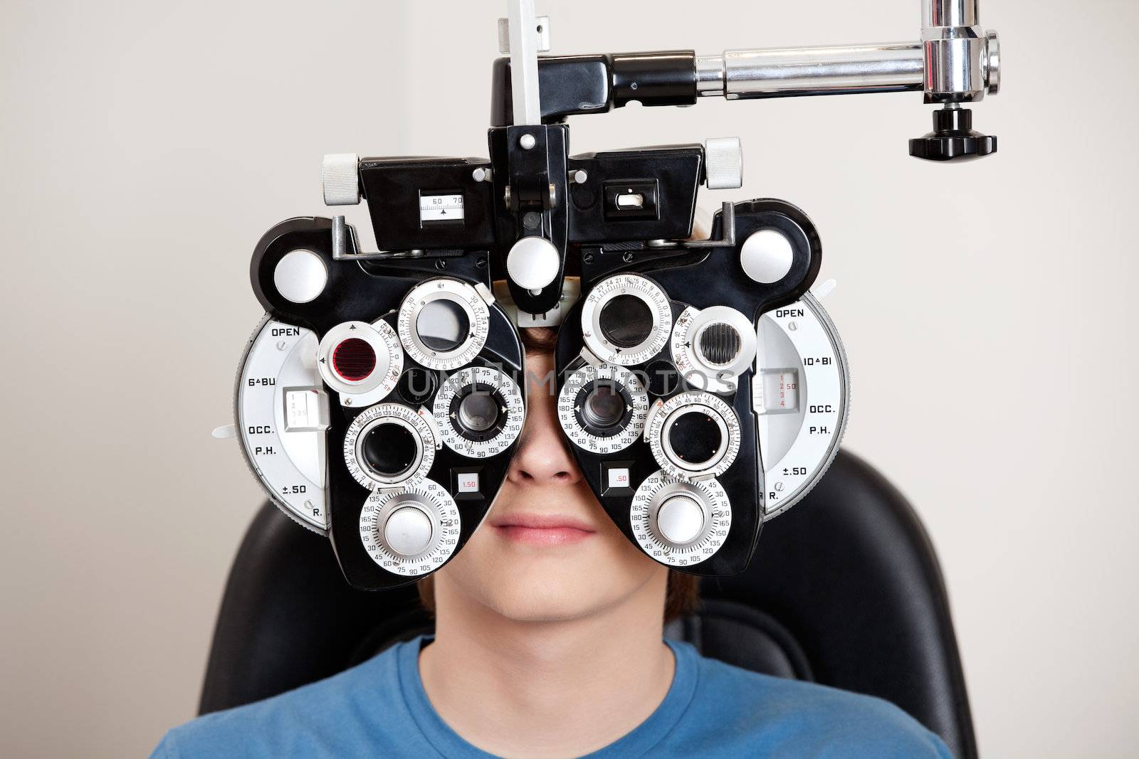 Boy sitting while undergoing an eye test with phoropter in the clinic