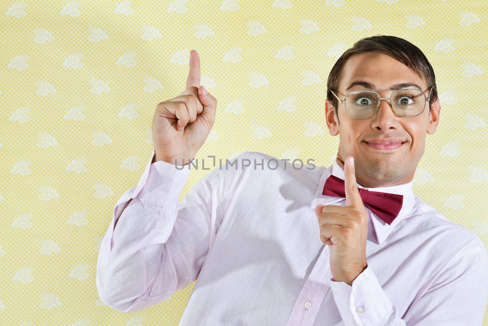 Portrait of young male geek pointing up over yellow textured background