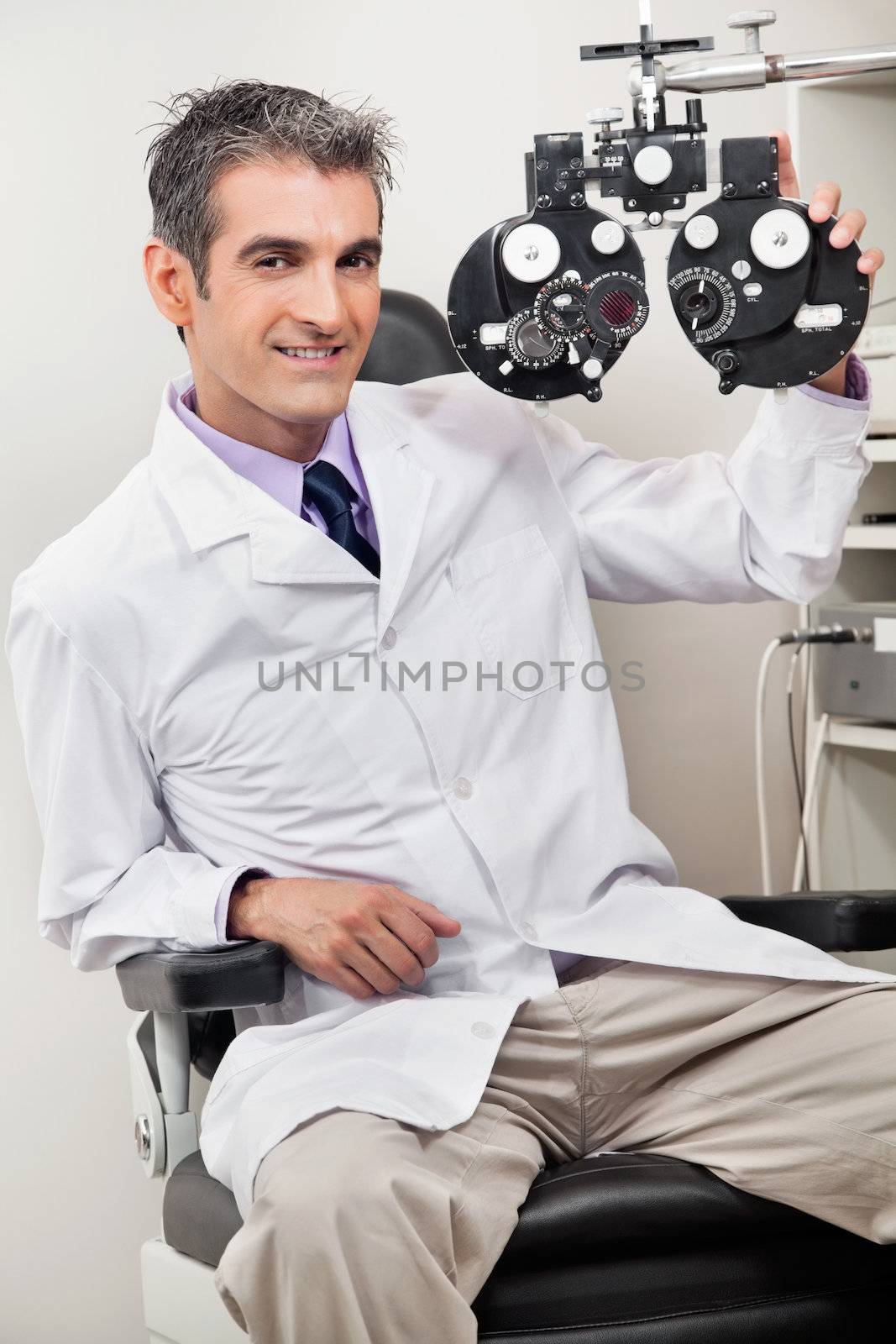 Portrait of male optometrist smiling with phoropter at his clinic