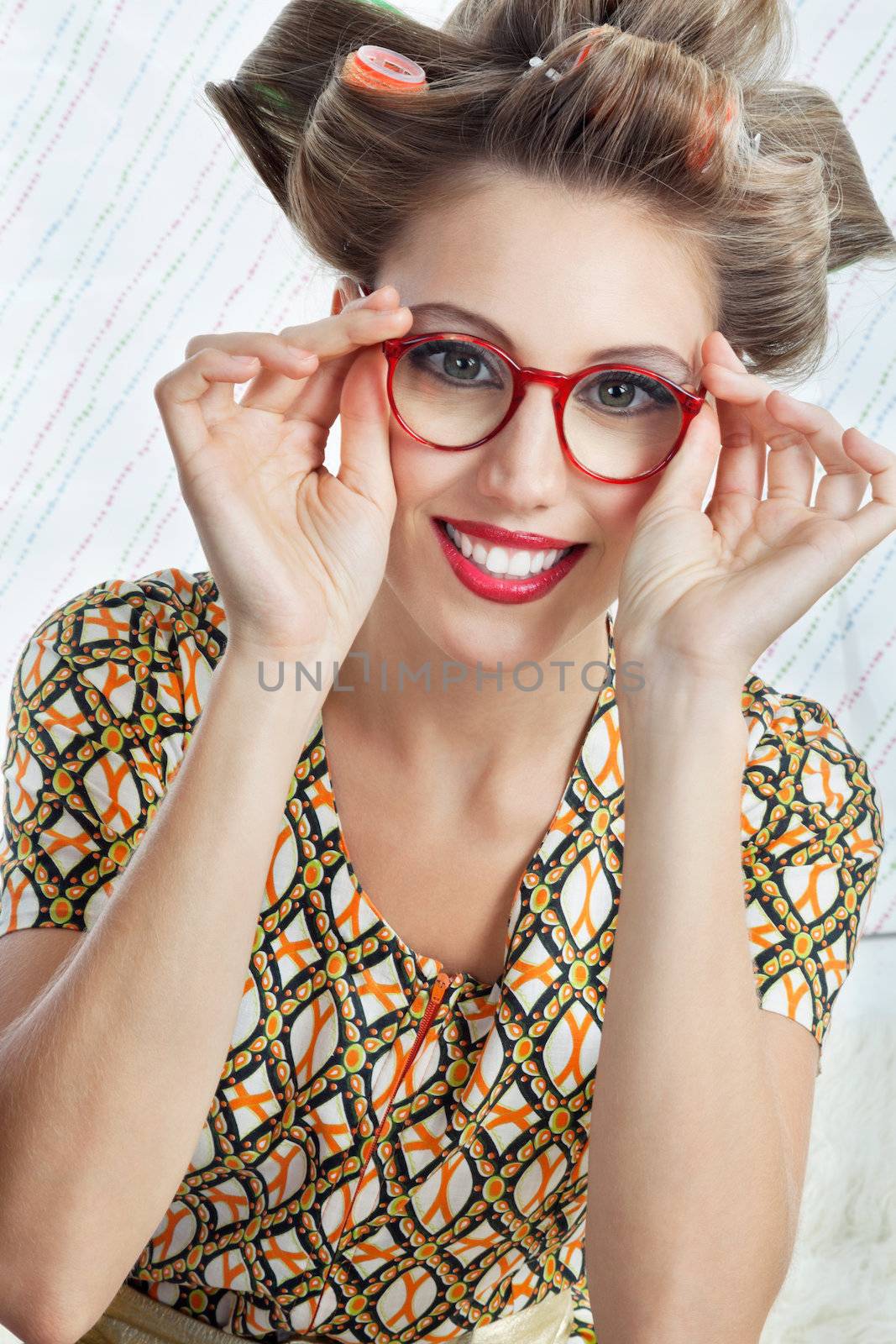 Portrait of young woman with hair curlers wearing red vintage eyeglasses