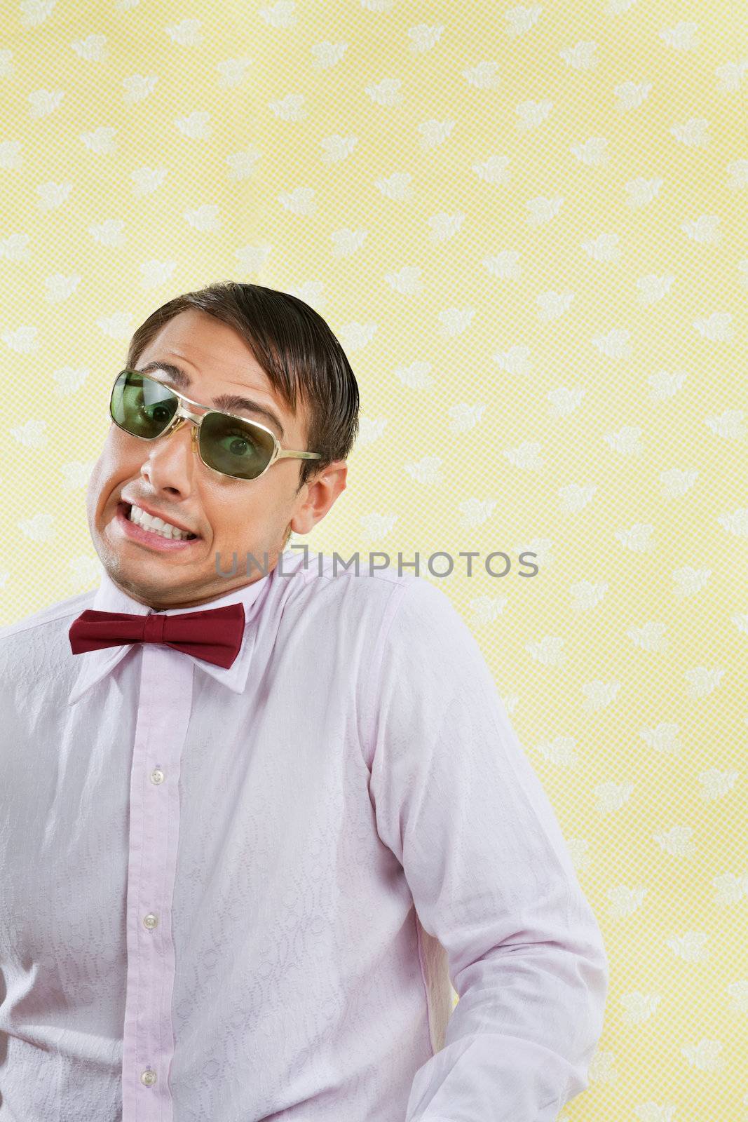 Portrait of funny male geek making a face over yellow wallpaper