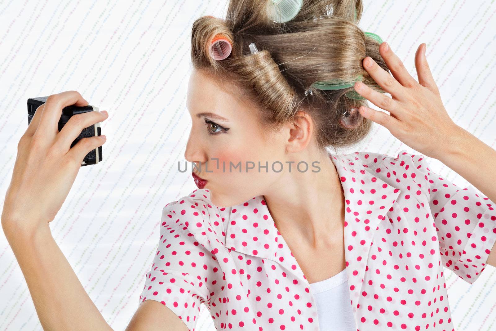 Young woman with hair curlers puckering while taking a self portrait through a vintage camera