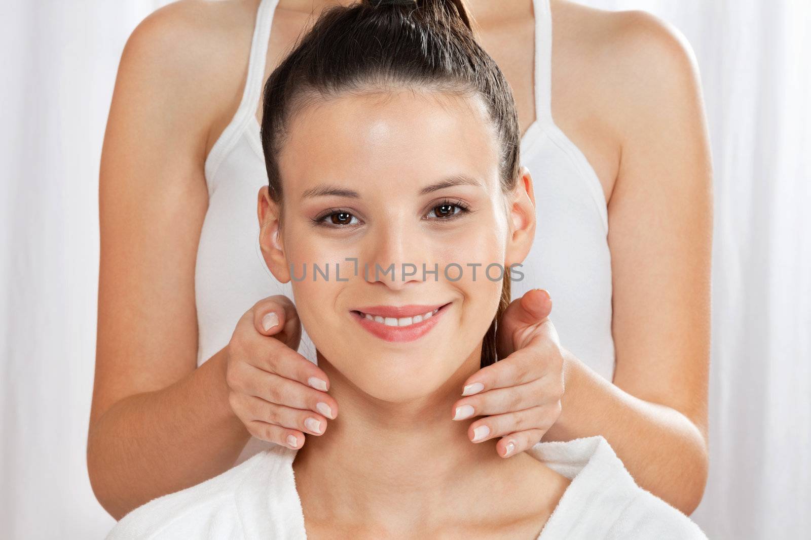 Portrait of beautiful young woman with female masseuse standing behind