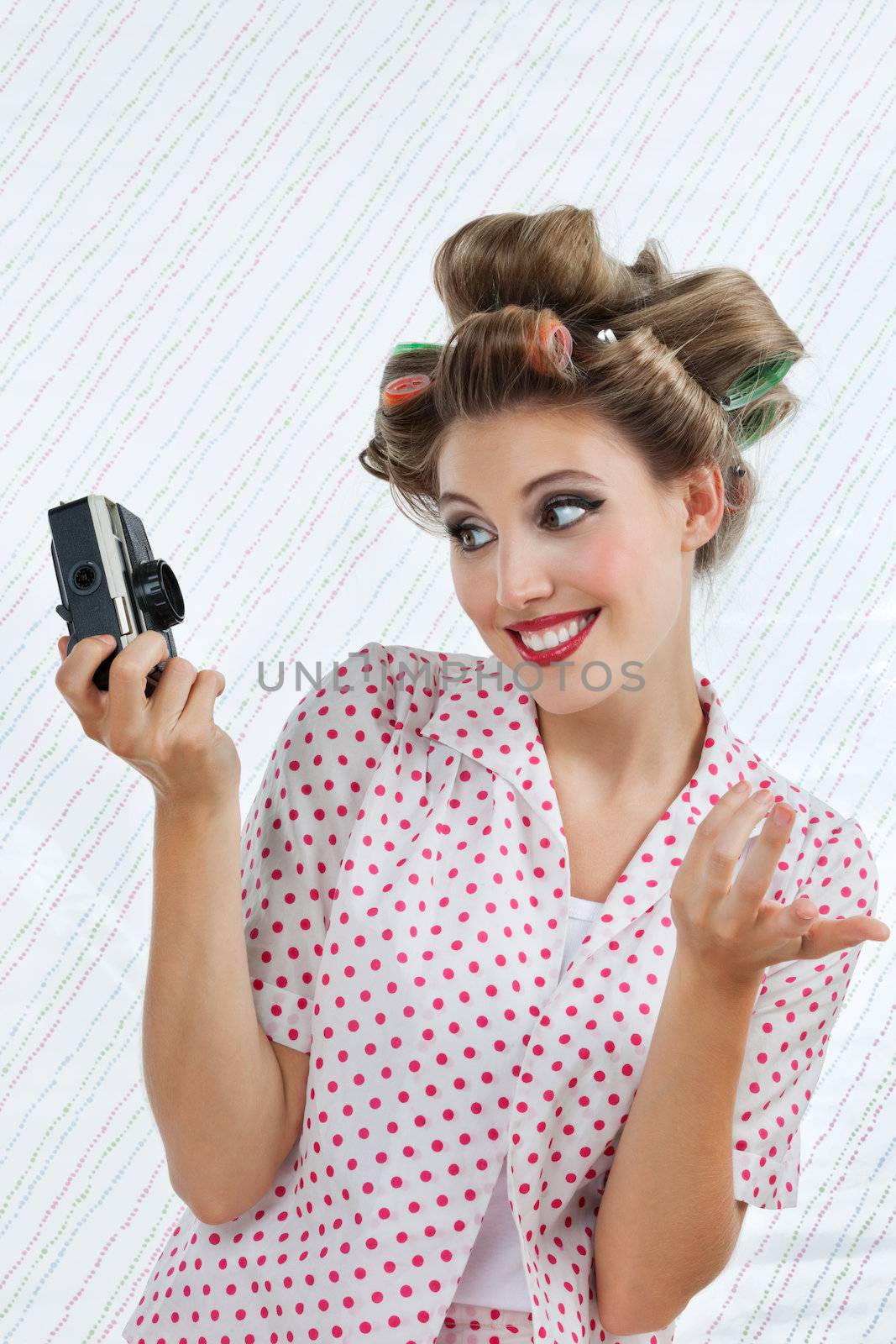 Beautiful young woman with hair curlers taking self portrait photograph through camera