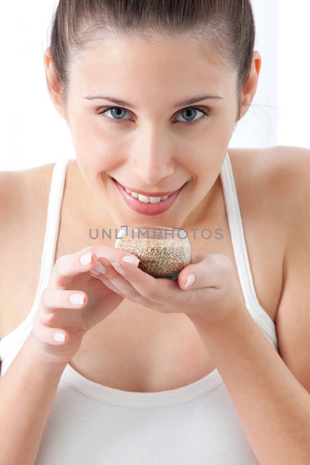 Young woman holding sesame seed in bowl.