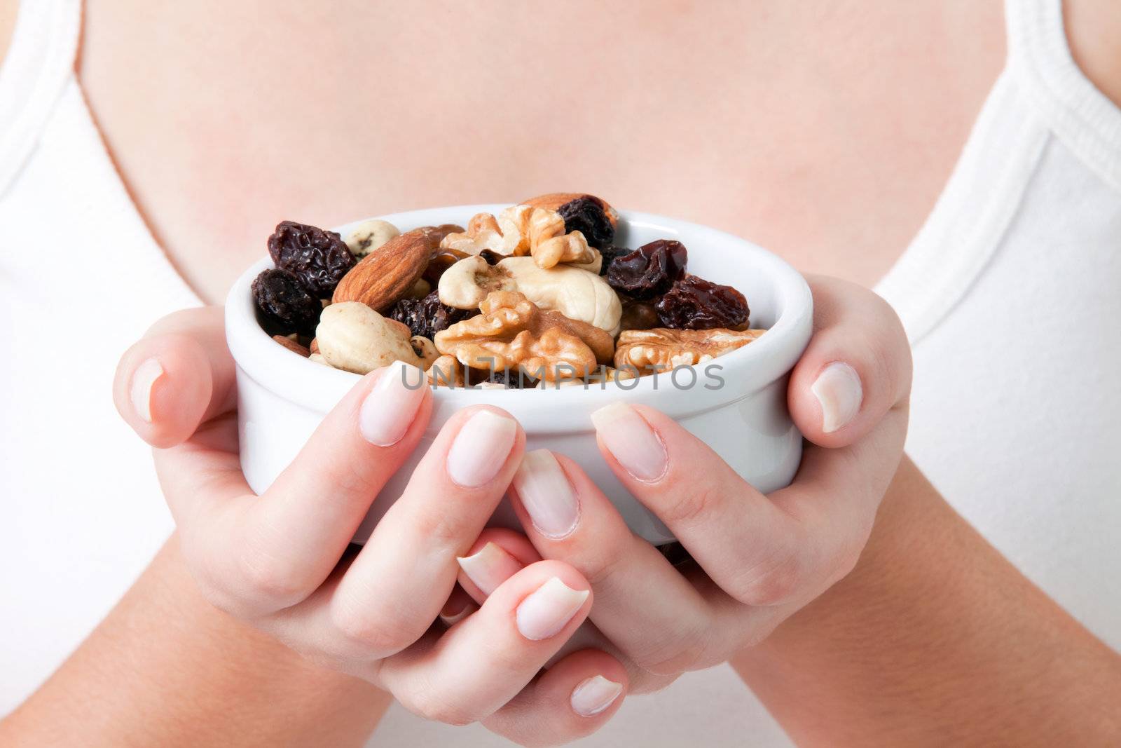 Close-up of woman holding bowl of dry fruits.