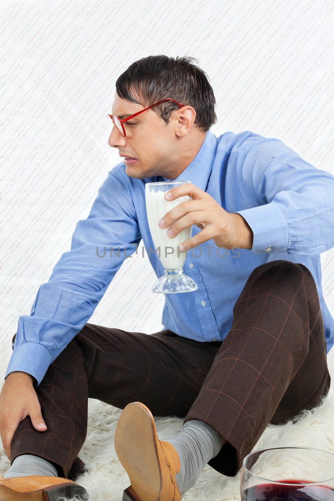Young male geek making a face while holding glass healthy drink