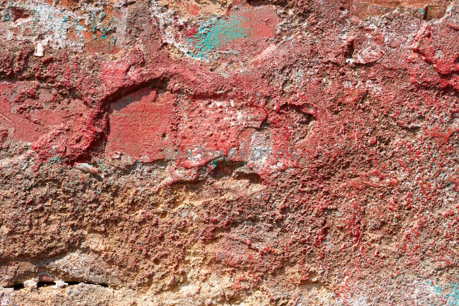 Part of ancient brick wall with plaster partly shelled and partially painted in red