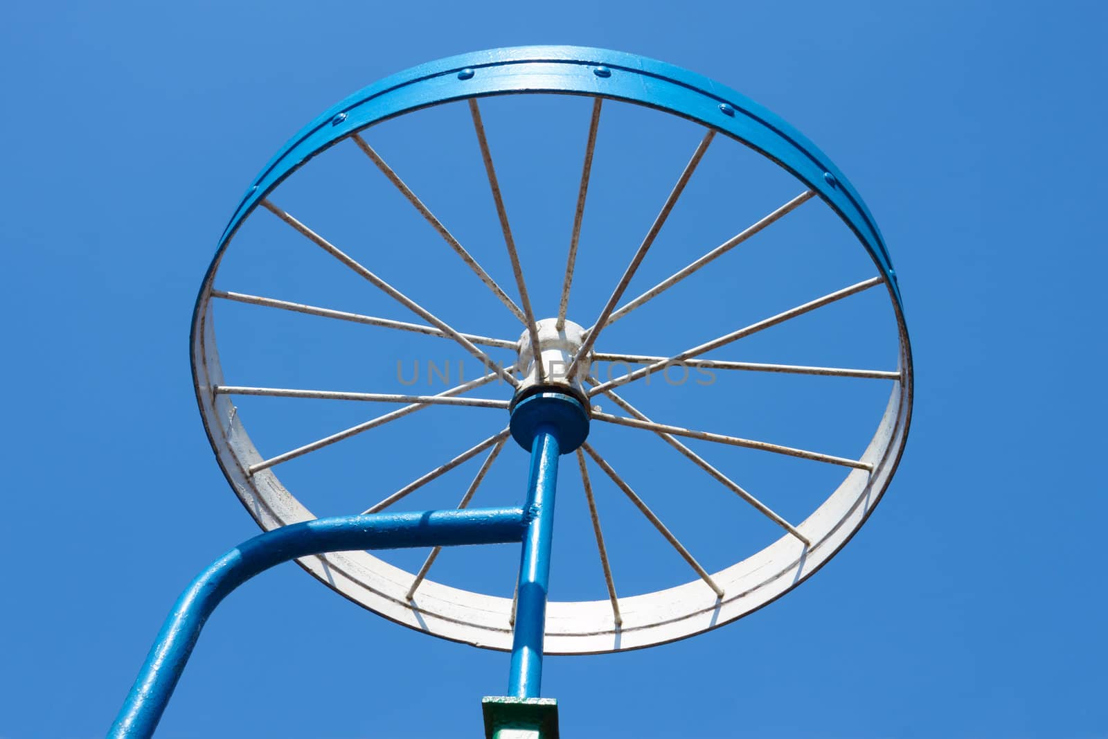 Metal painted detail in the form of a bicycle wheel on the blue sky background