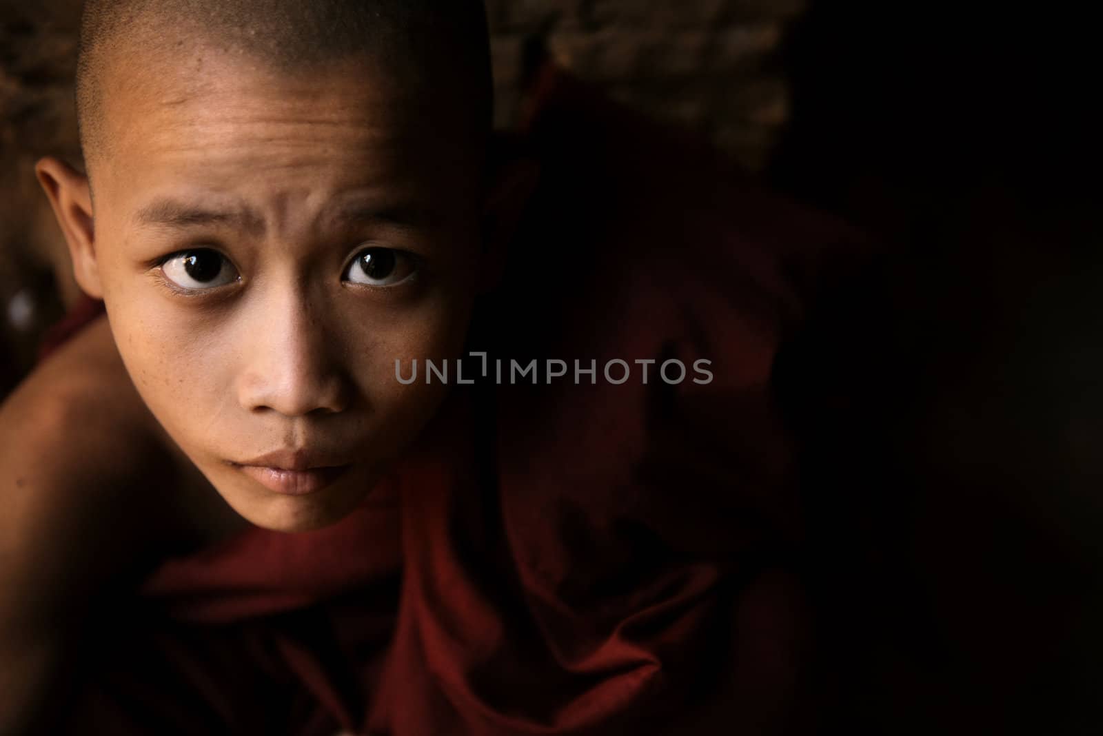 Portrait of a little monk, low light inside temple