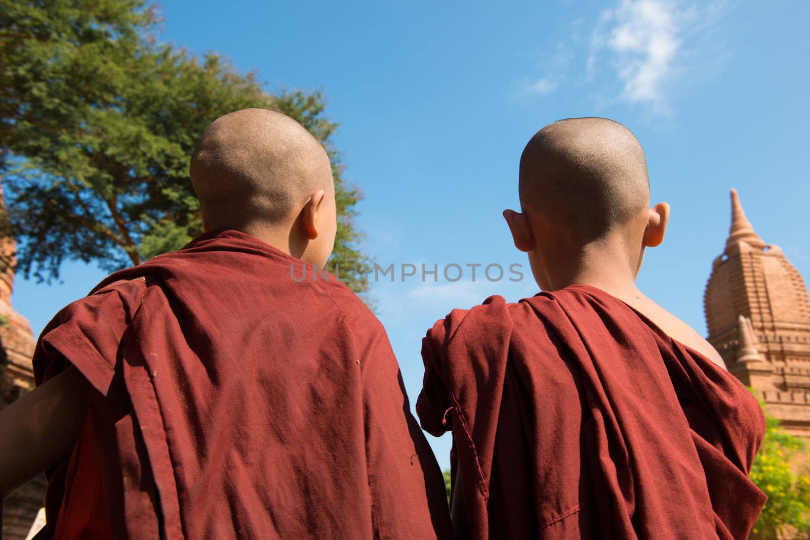 Rear view of two little monks standing under hot sun at Bagan, Myanmar