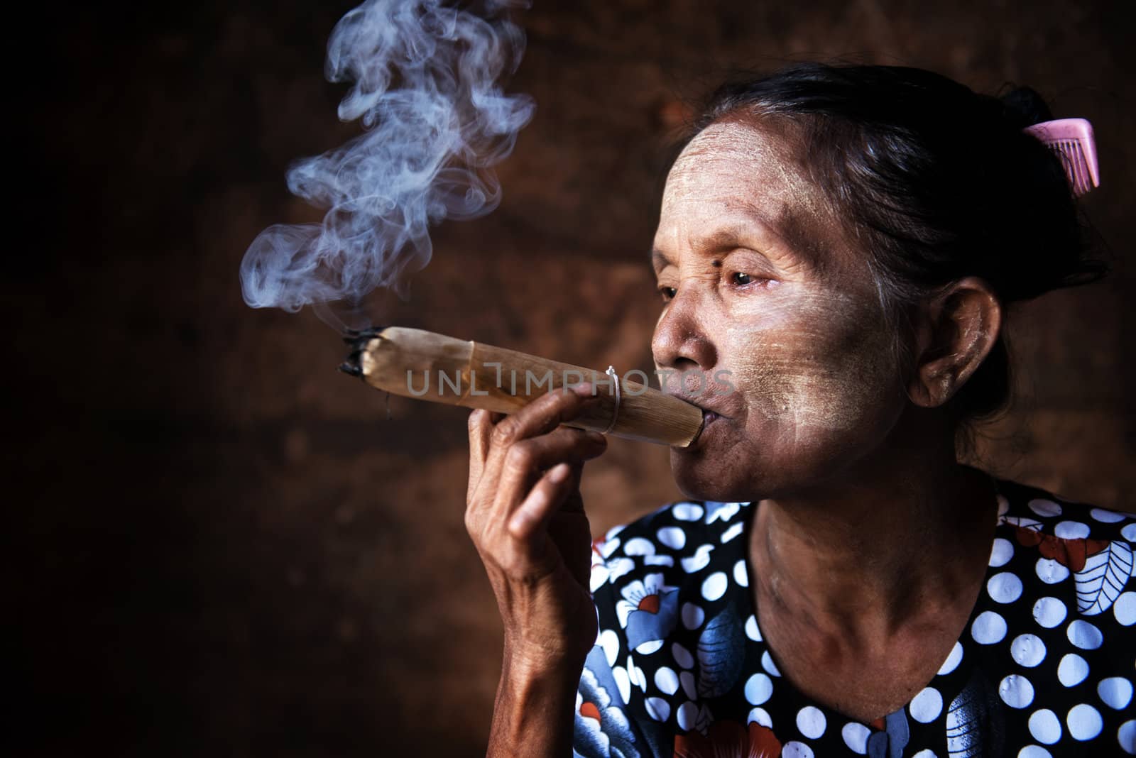 Old wrinkled Asian woman smoking traditional tobacco. Bagan, Myanmar.