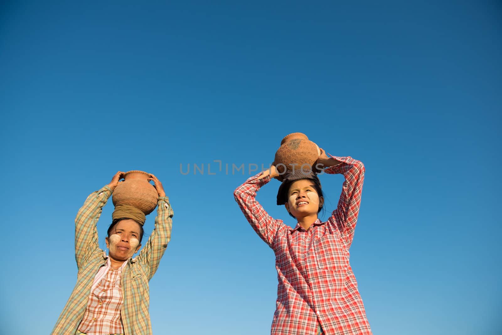 Asian traditional farmers carrying clay pot on head going back home, Bagan, Myanmar