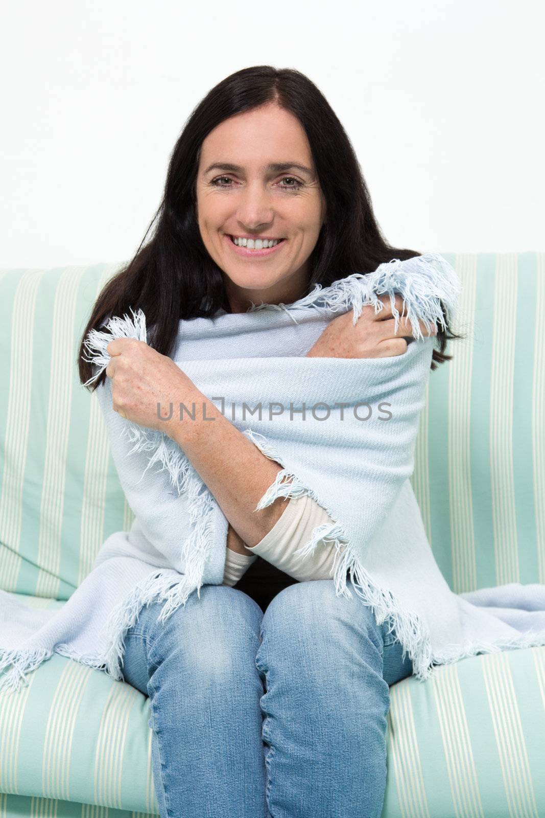 Black haired woman with a blanket sitting on a couch