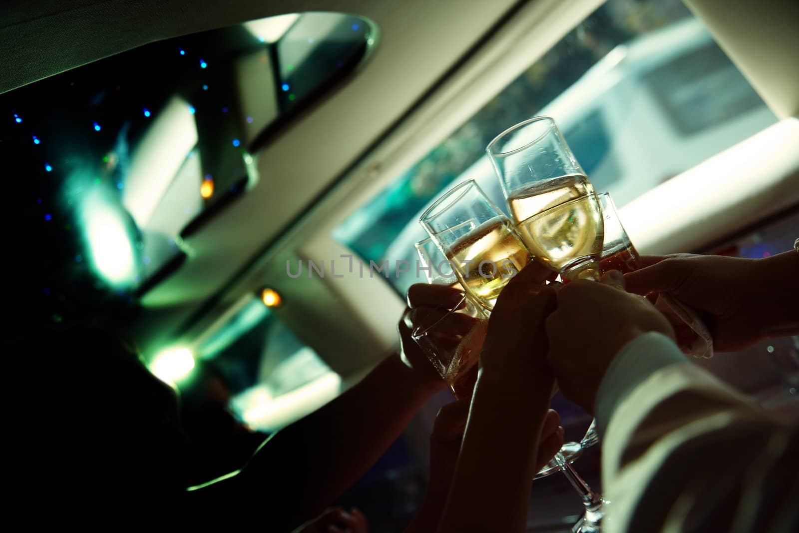 Casual photo of the human hand holding wine glasses in limousine 