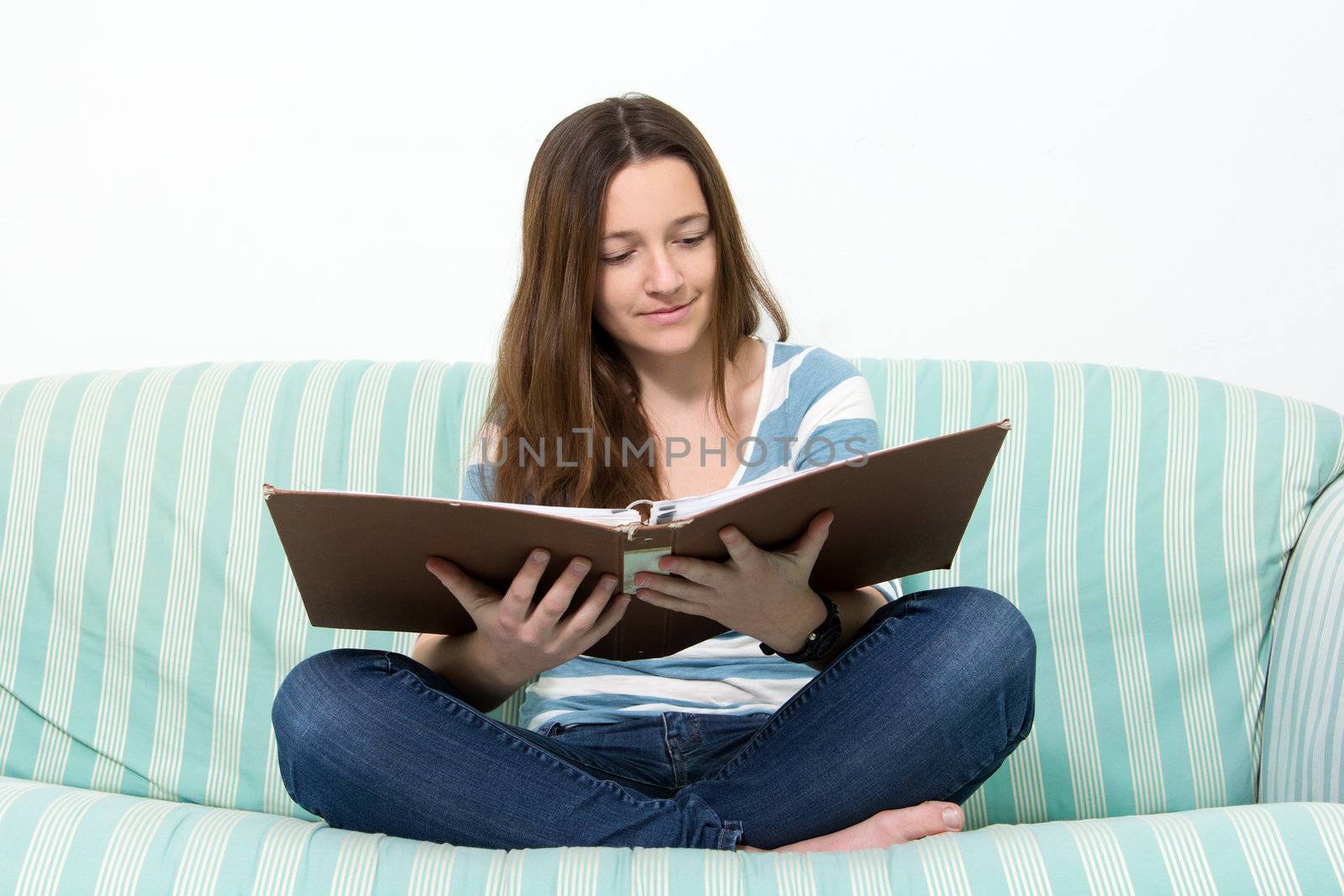 Young Brunette Teenager with blue jeans studying on couch