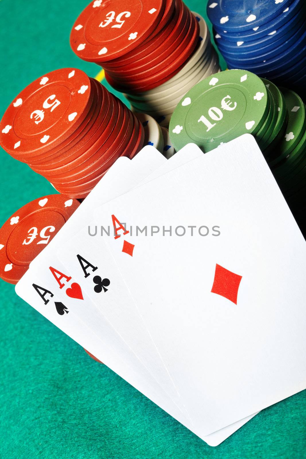 Set of four aces and poker chips on a green table