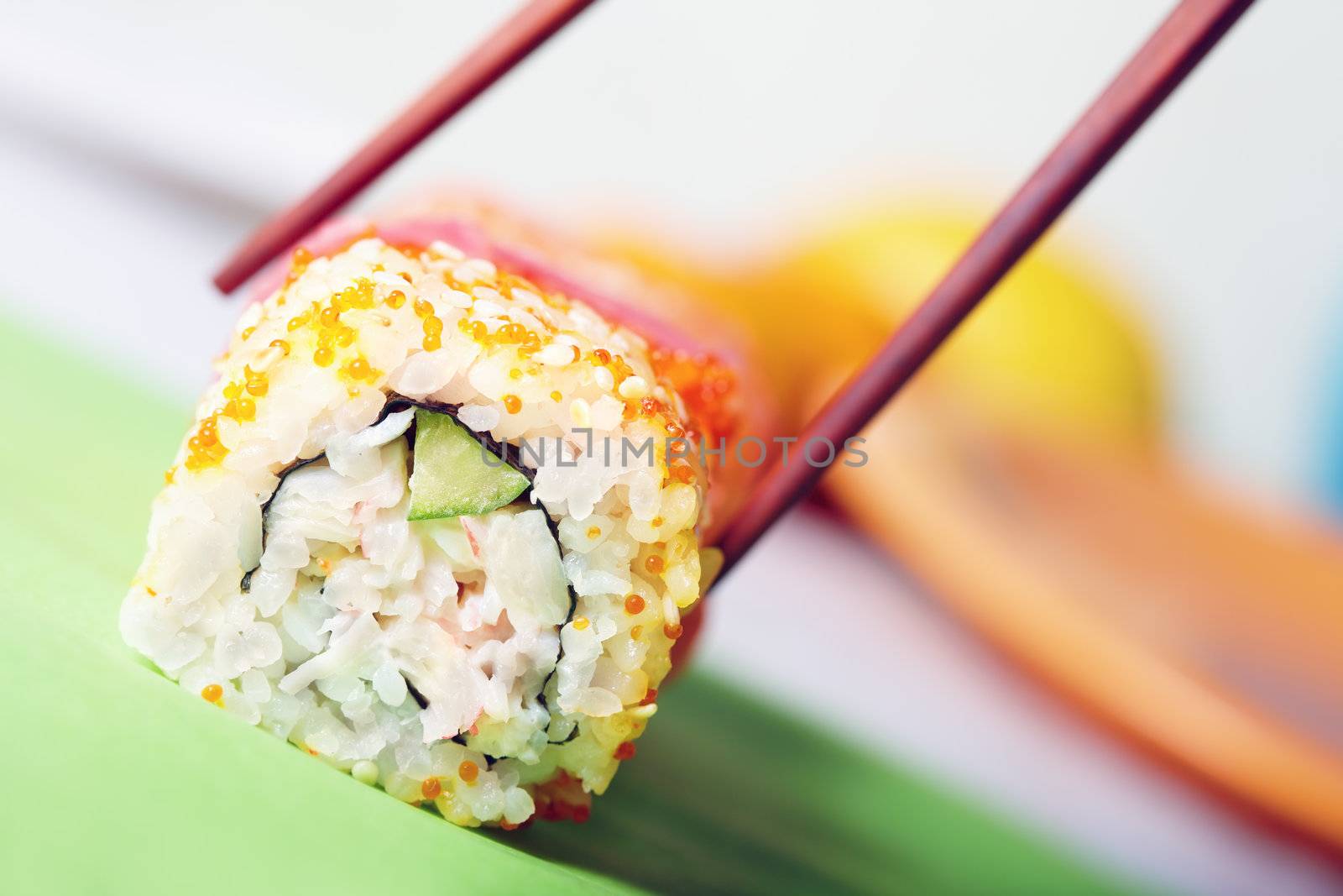 Close-up horizontal photo of the rolled sushi with rice and cucumber on the table and chopsticks
