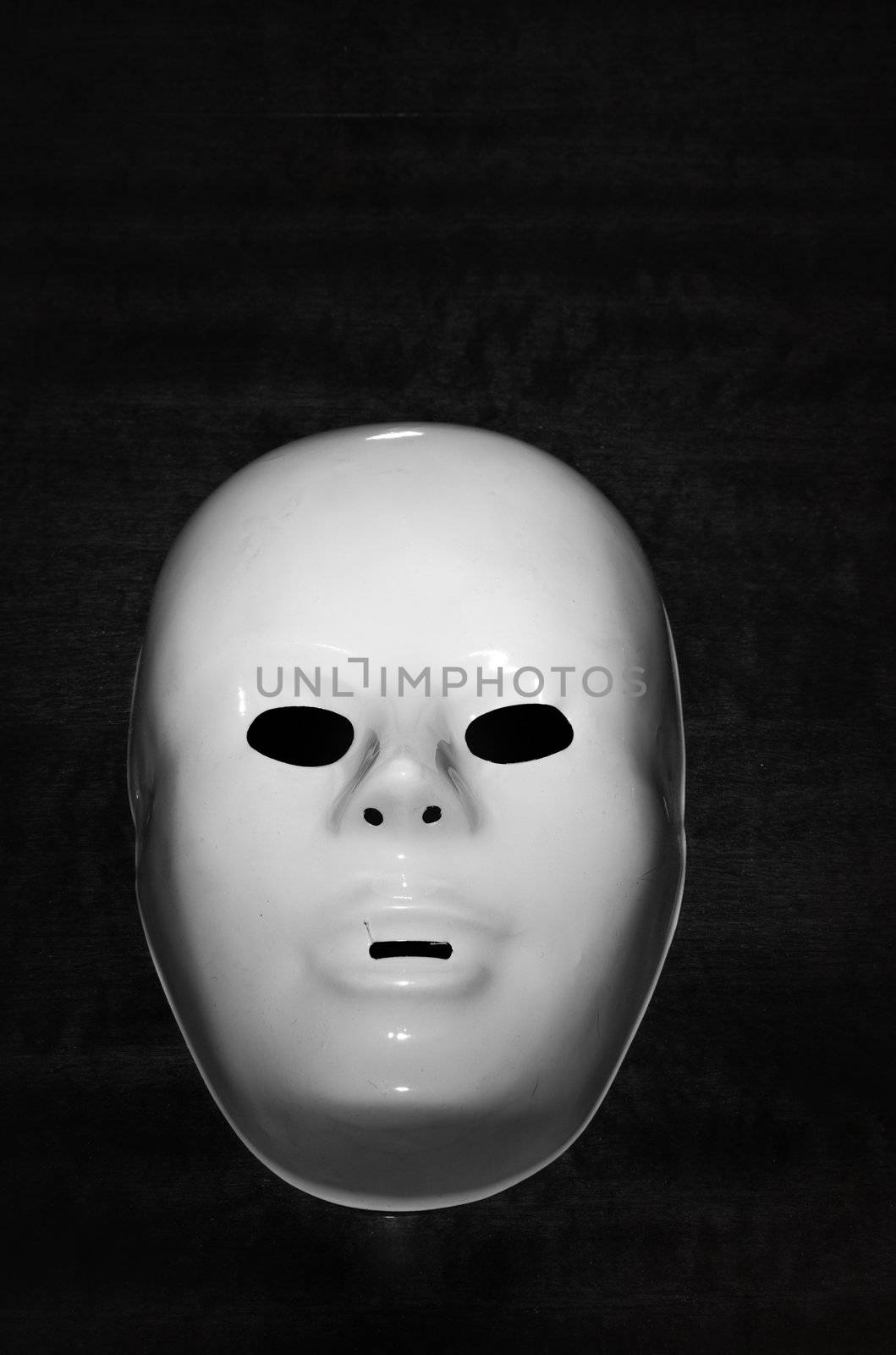 Plastic mask on a dark background as horror symbol