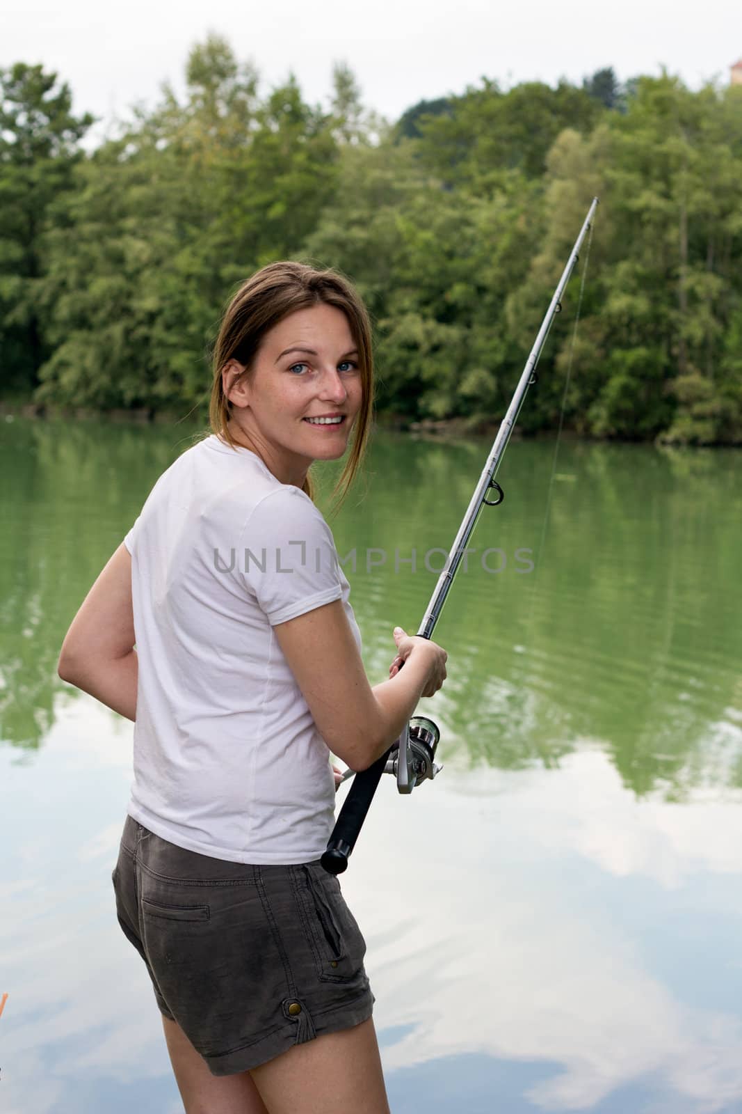 Brunette Woman Fishing at a lake with green water