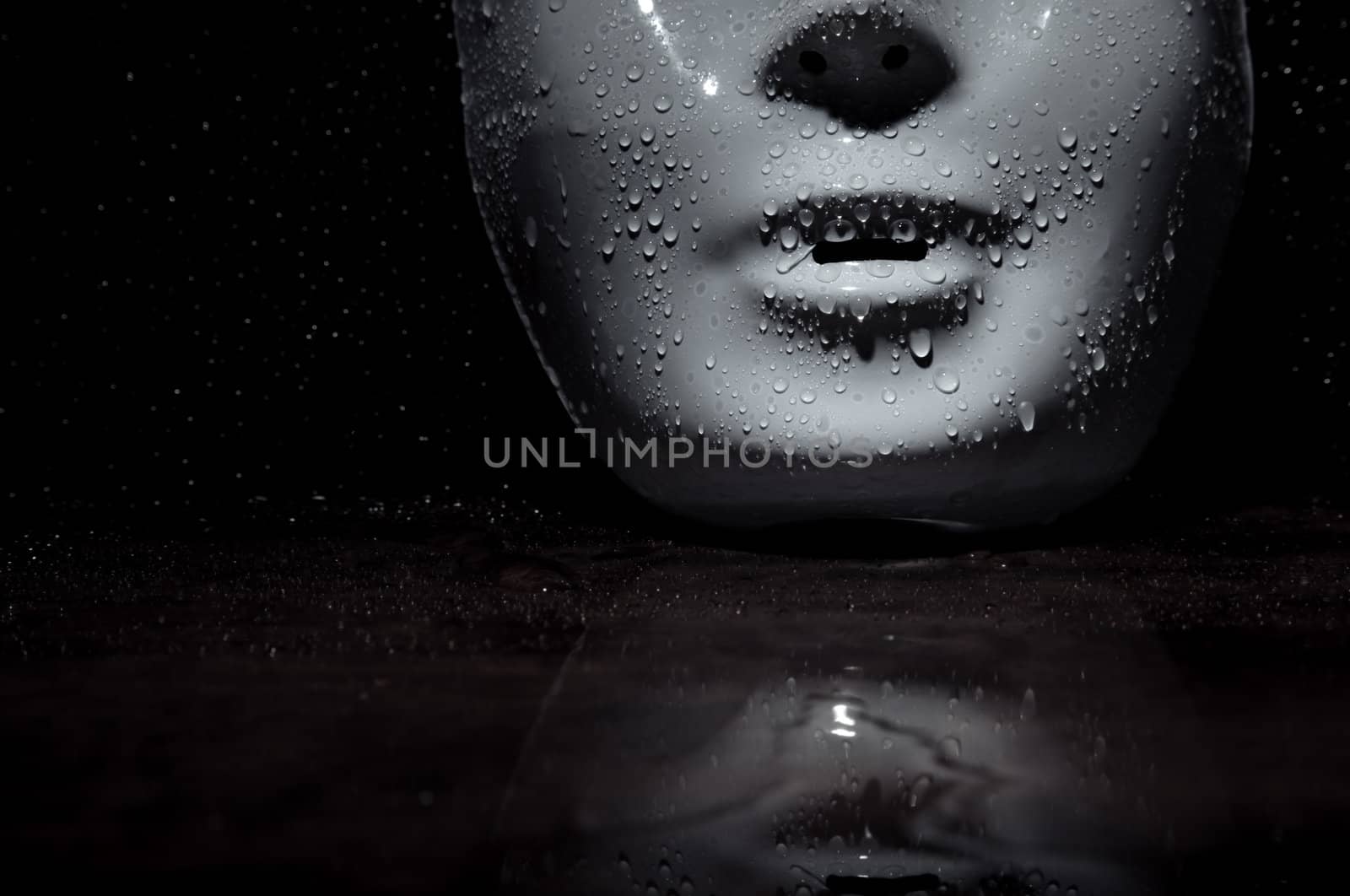 Wet plastic mask on a dark wooden background. Close-up photo