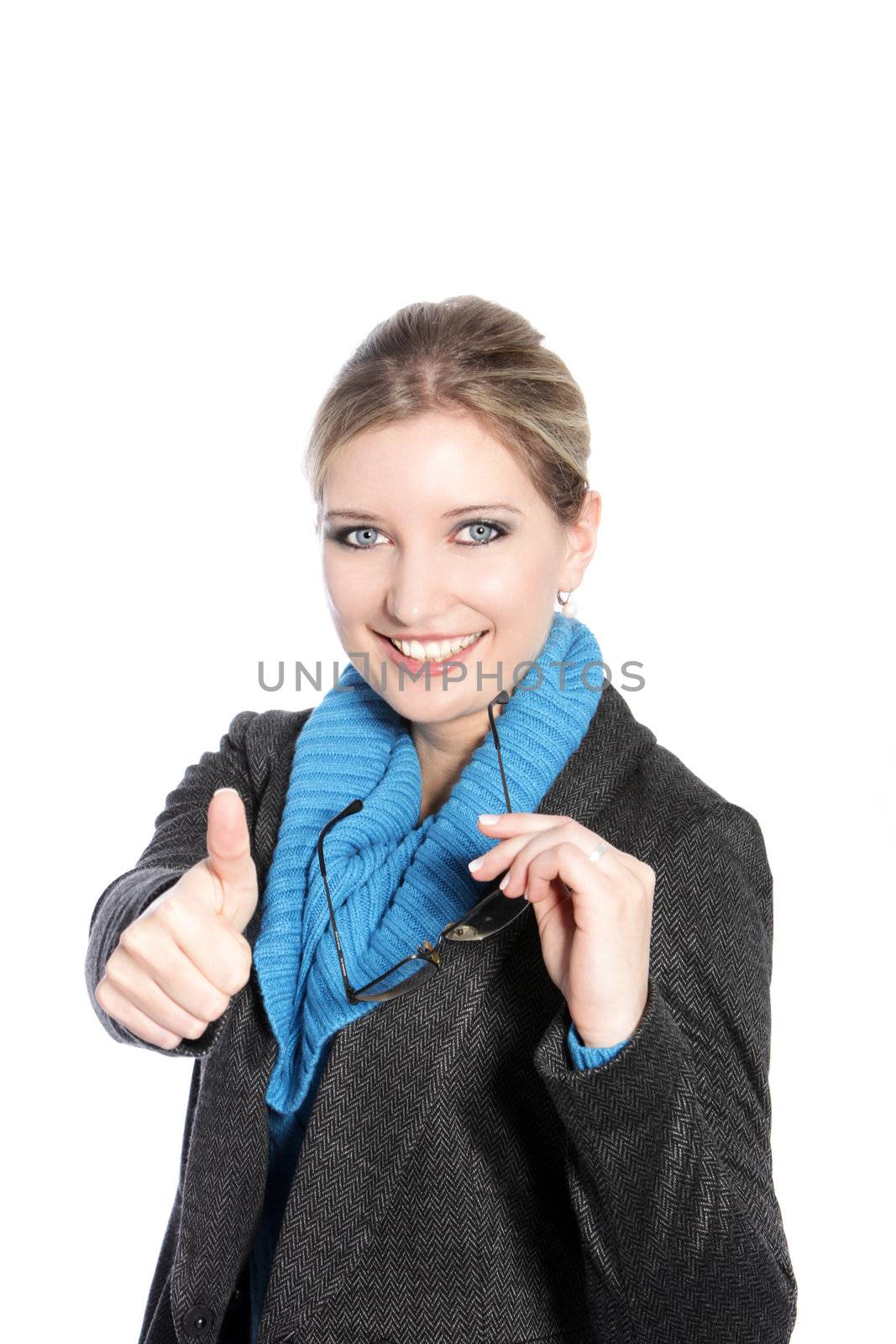 Beautiful blond woman in winter attire giving a thumbs up to show that everything is going well and has her approval isolated on white