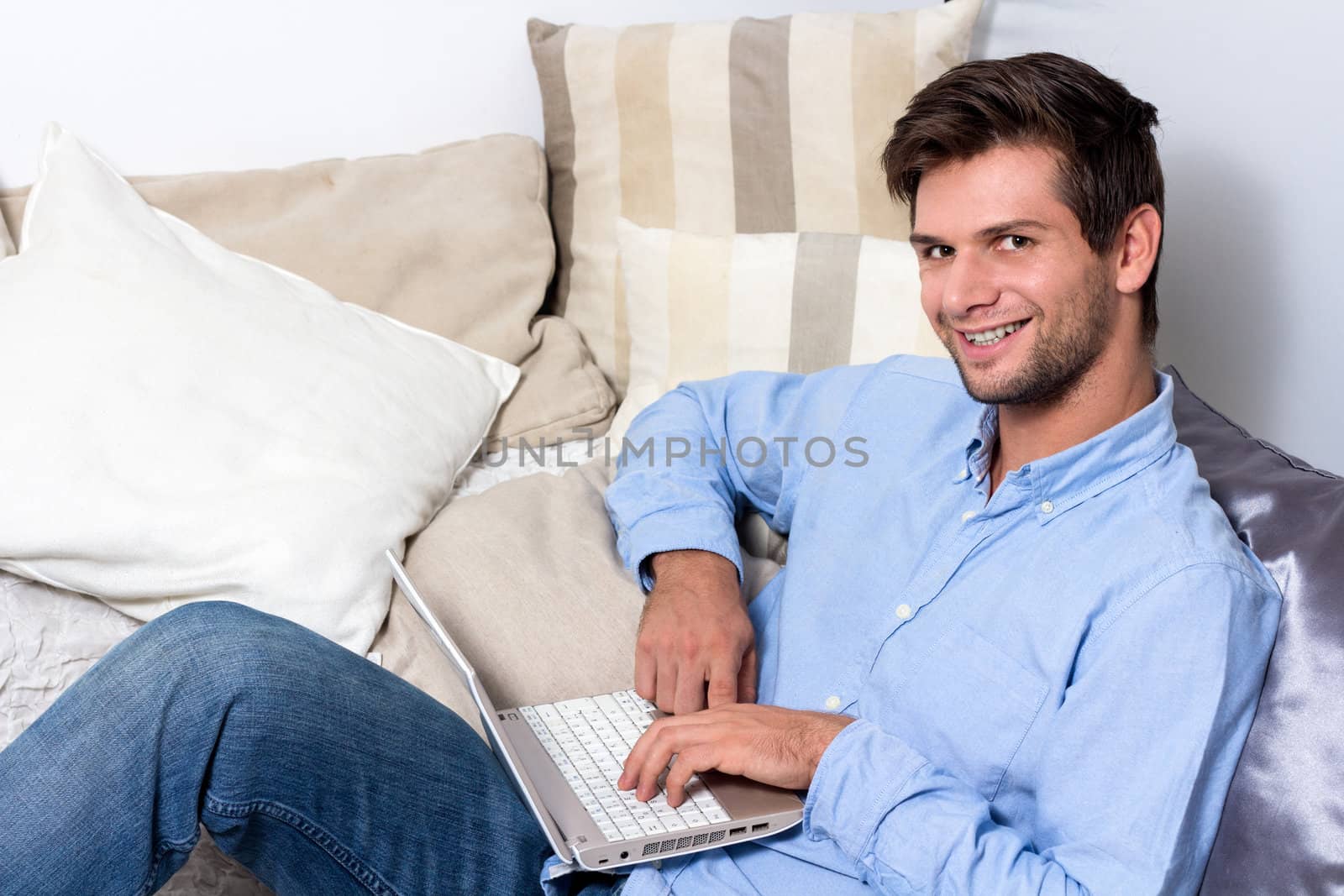 Young man using laptop on couch by dwaschnig_photo