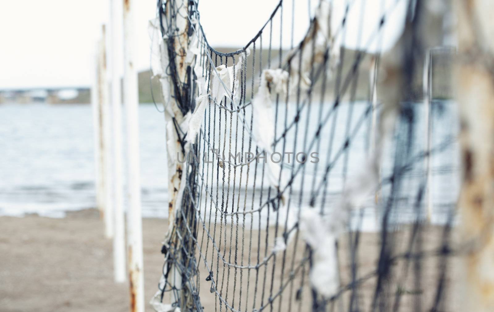 Old net attached to the poles at the beach. Shallow depth of field added for more natural view