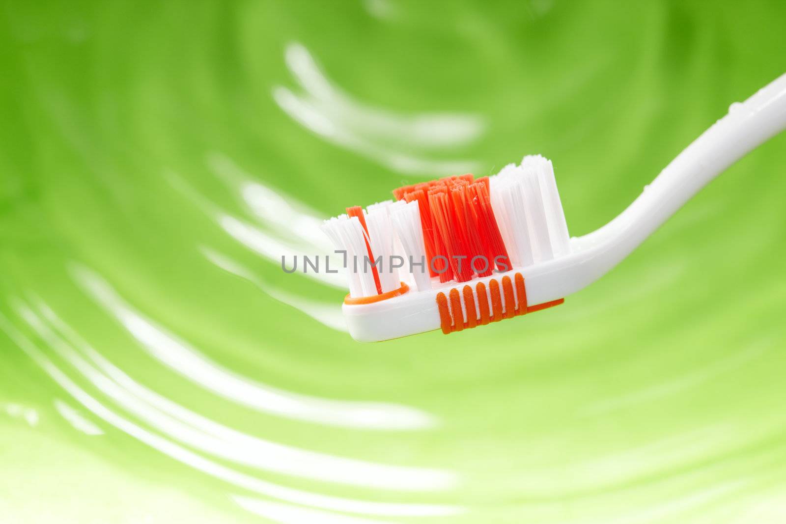 Close-up photo of the toothbrush on a green water background. Natural colors