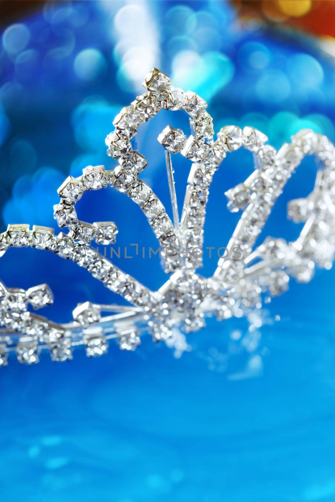 Close-up photo of the silver diadem with diamonds on a blue background with bokeh. Shallow depth of field added by macro lens for natural view