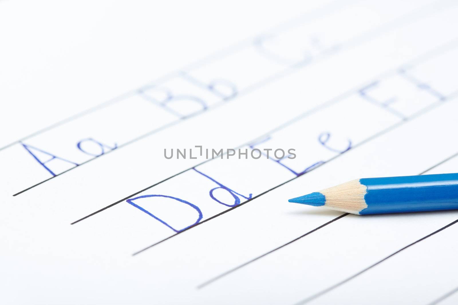 Blue pencil on a paper with alphabet. Close-up photo with shallow depth of field