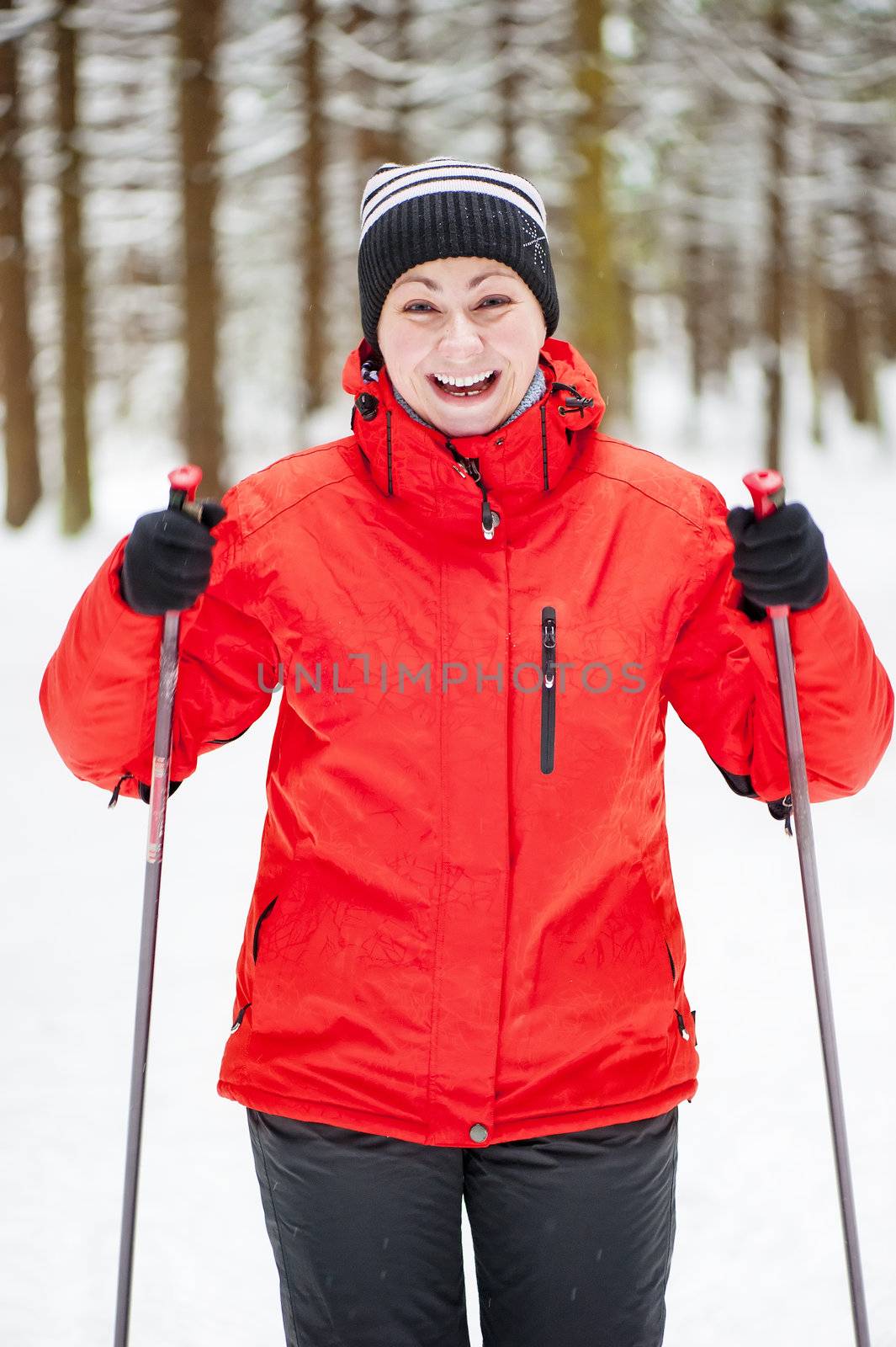 Happy girl posing on skis in the winter woods.