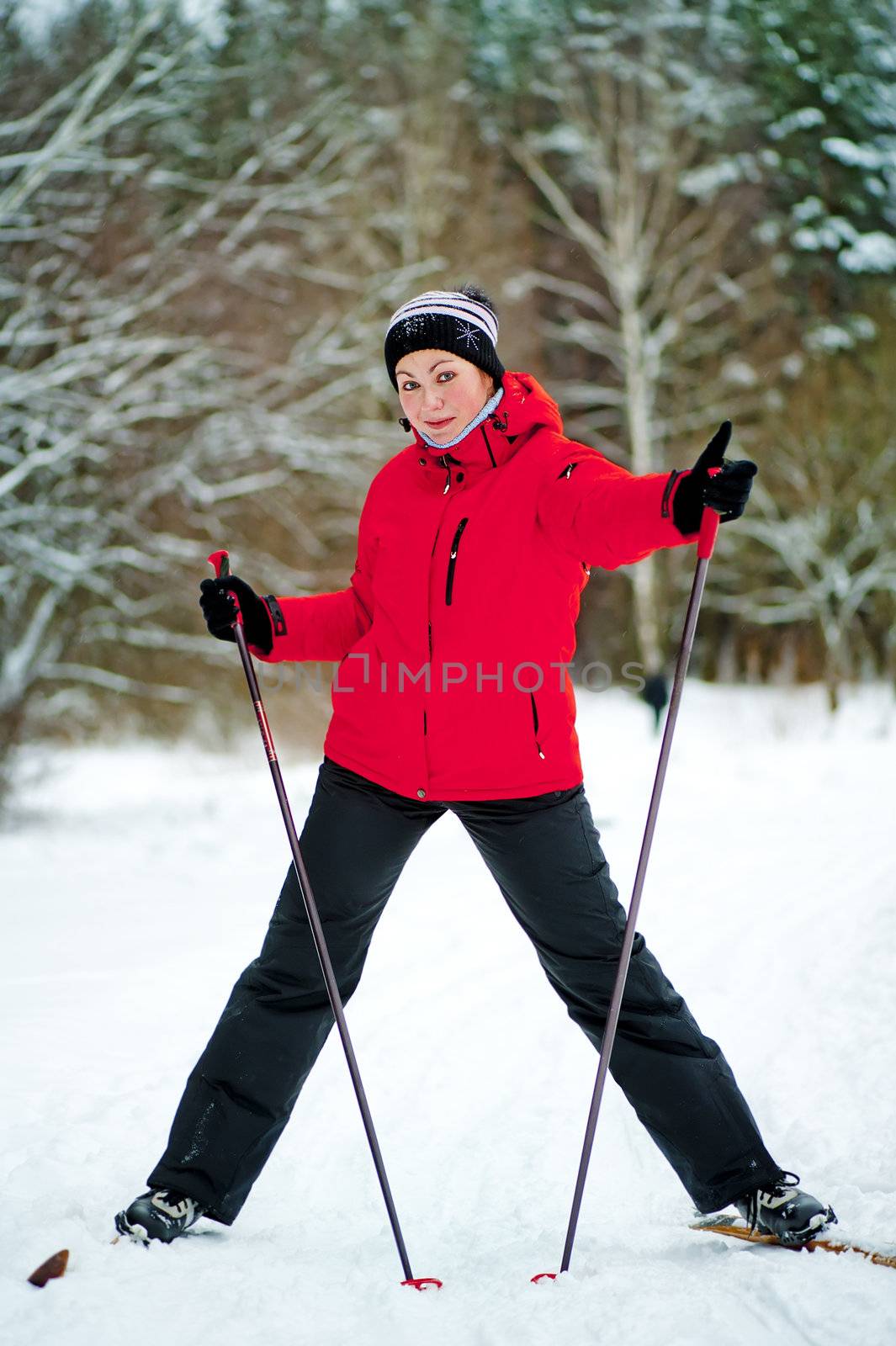 Happy girl posing on skis in the winter woods.