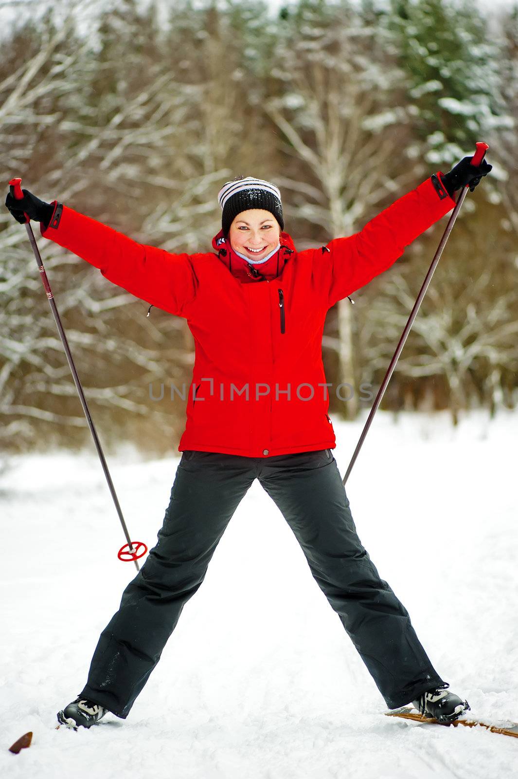Happy girl posing on skis in the winter woods.