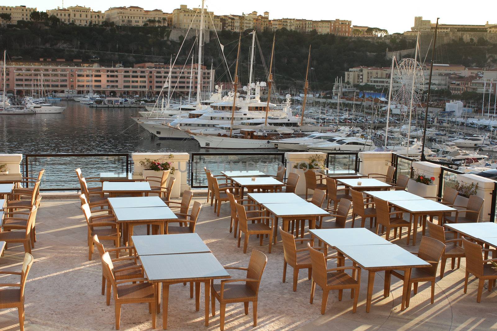 Restaurant at the harbor of monaco with yachts in the background