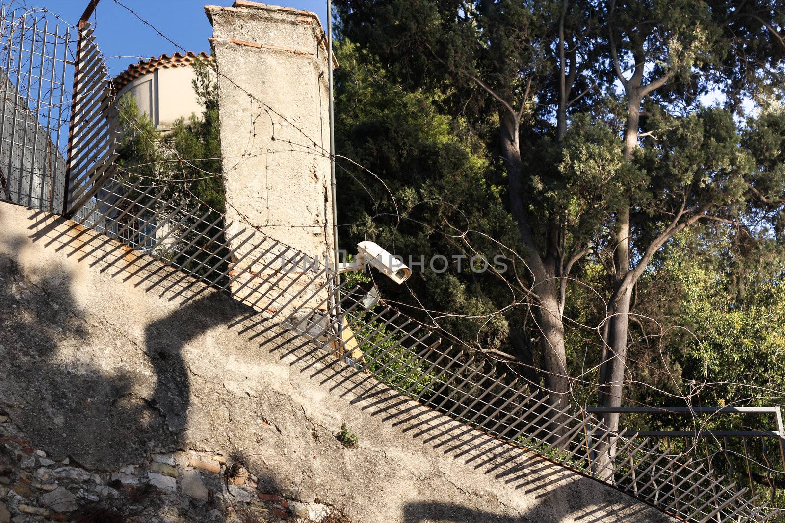 Surveillance Camera on a stone wall with barbed fence